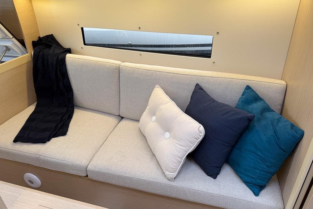Interior of 2023 Beneteau Oceanis 30.1 yacht with cozy sofa and cushions.