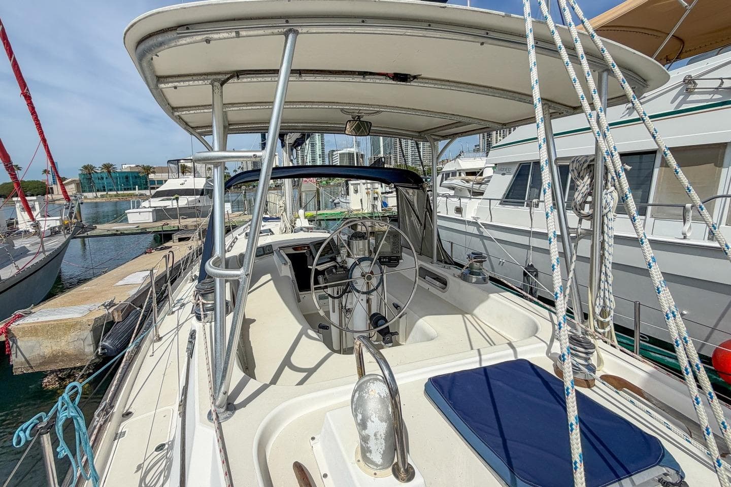 1984 Pearson 385 sailboat cockpit with steering wheel, docked at marina, surrounded by other boats.
