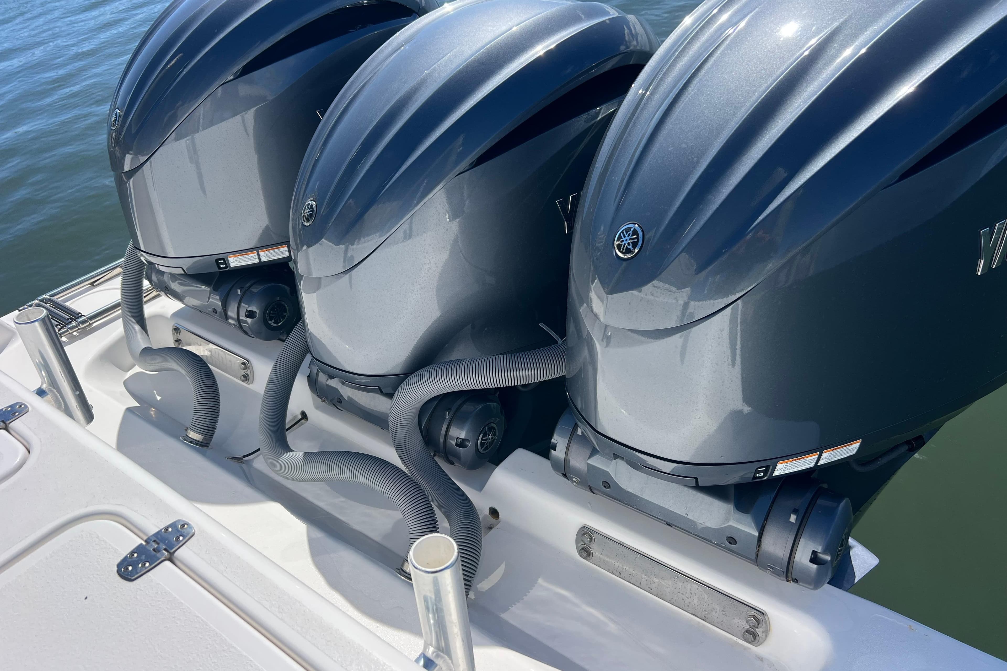 Triple outboard engines on a 2023 Contender 39 ST boat, docked on water.