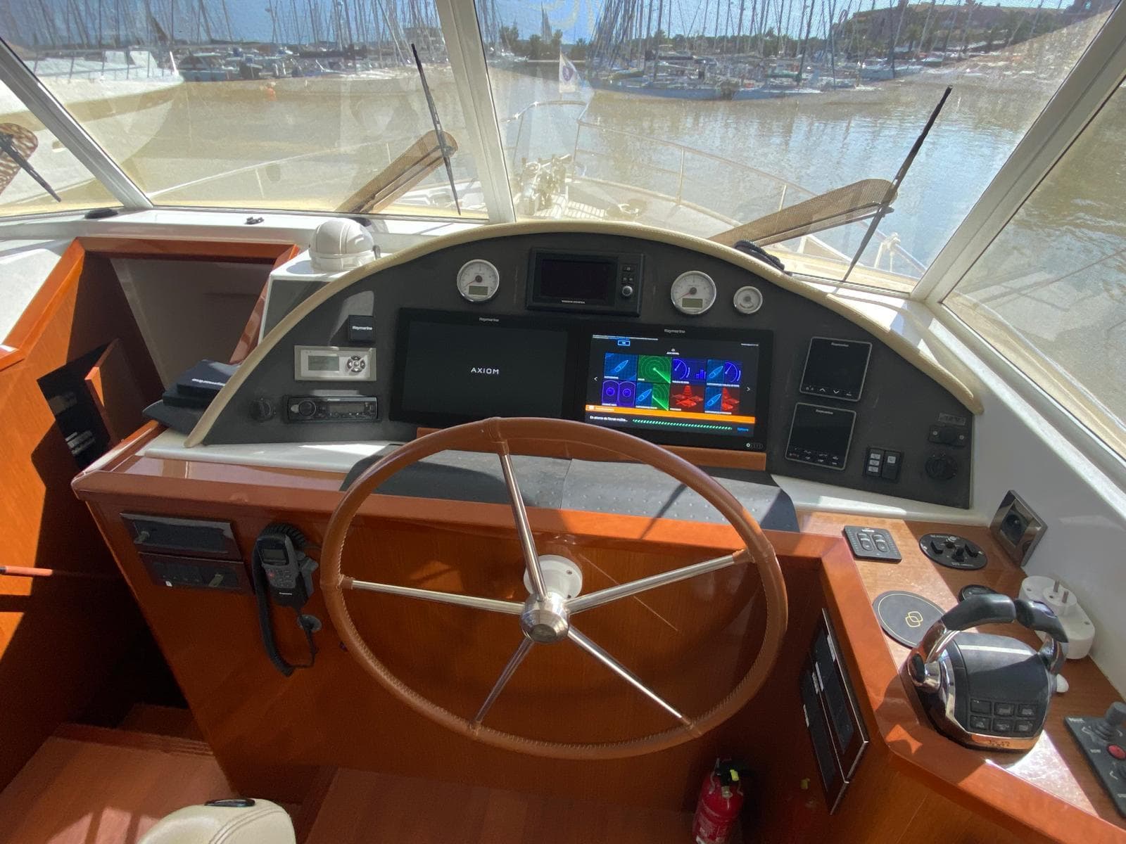 Helm of 2011 Beneteau Swift Trawler 52 with navigation equipment and wooden steering wheel.