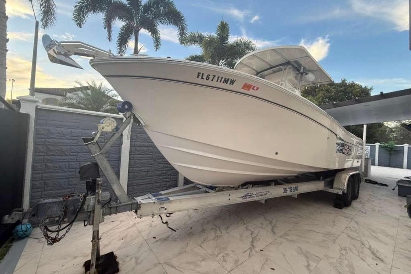 2004 Grady-White Chase 273 boat on trailer, parked outdoors with palm trees.