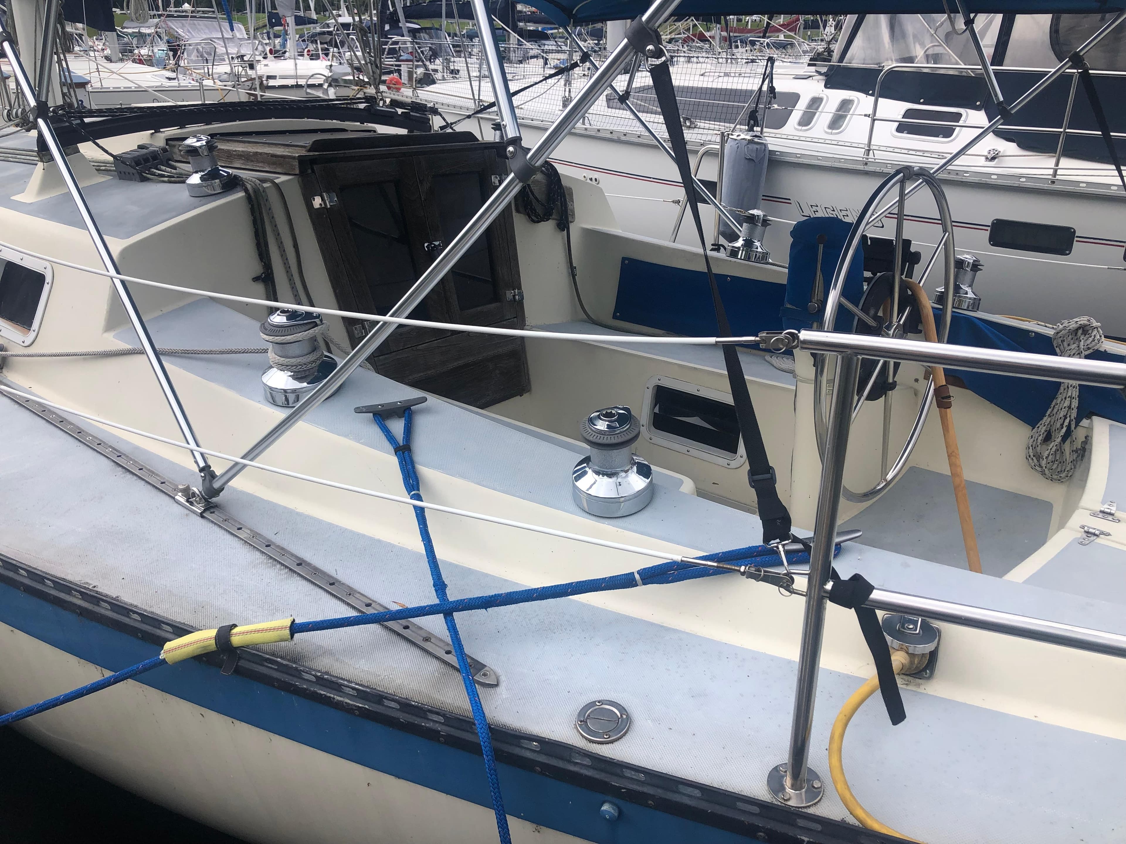 1980 Lancer 36 sailboat cockpit with steering wheel and winches, docked at marina.