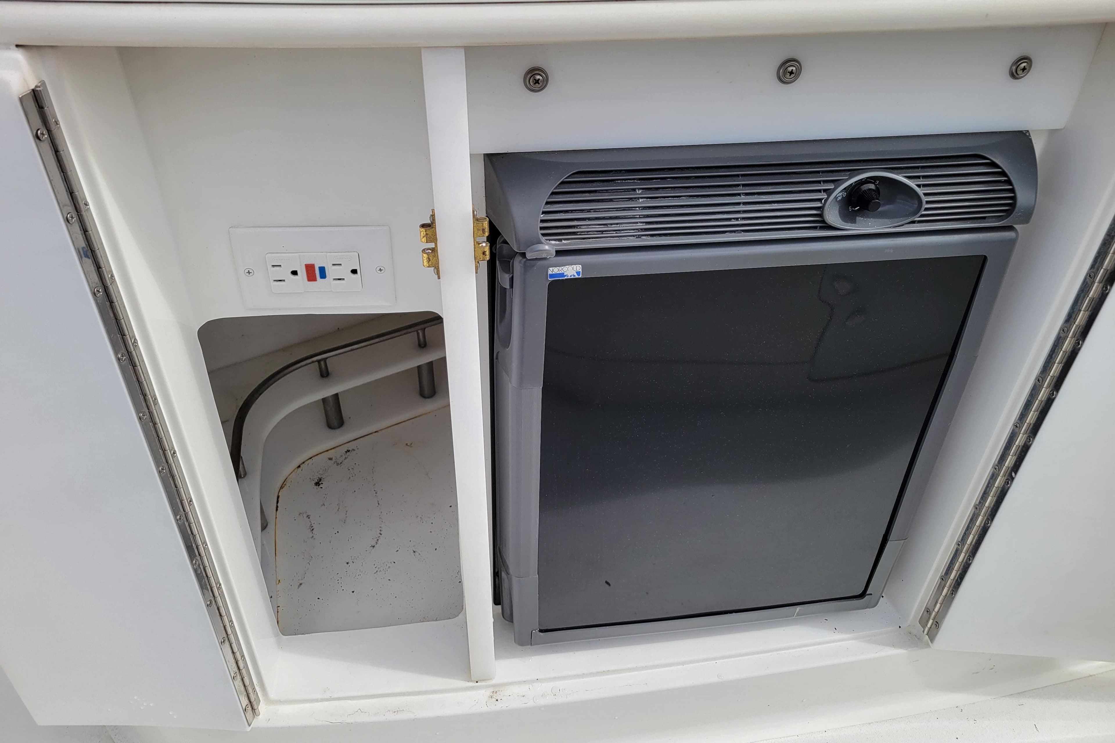 2002 Cobalt 293 boat interior with a small refrigerator and electrical outlet.