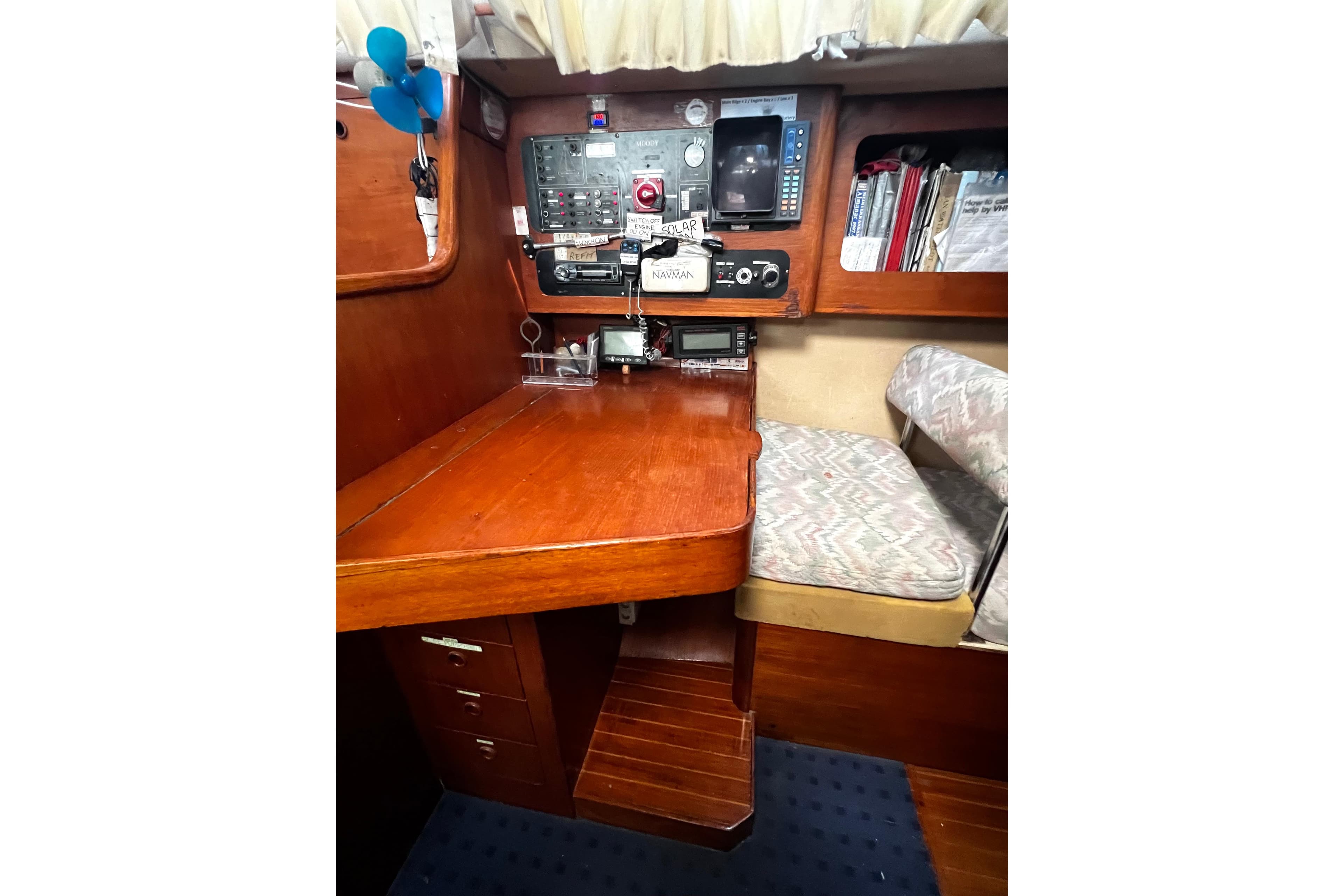 Navigation station inside a 1990 Moody 376 sailboat, featuring control panels and seating.