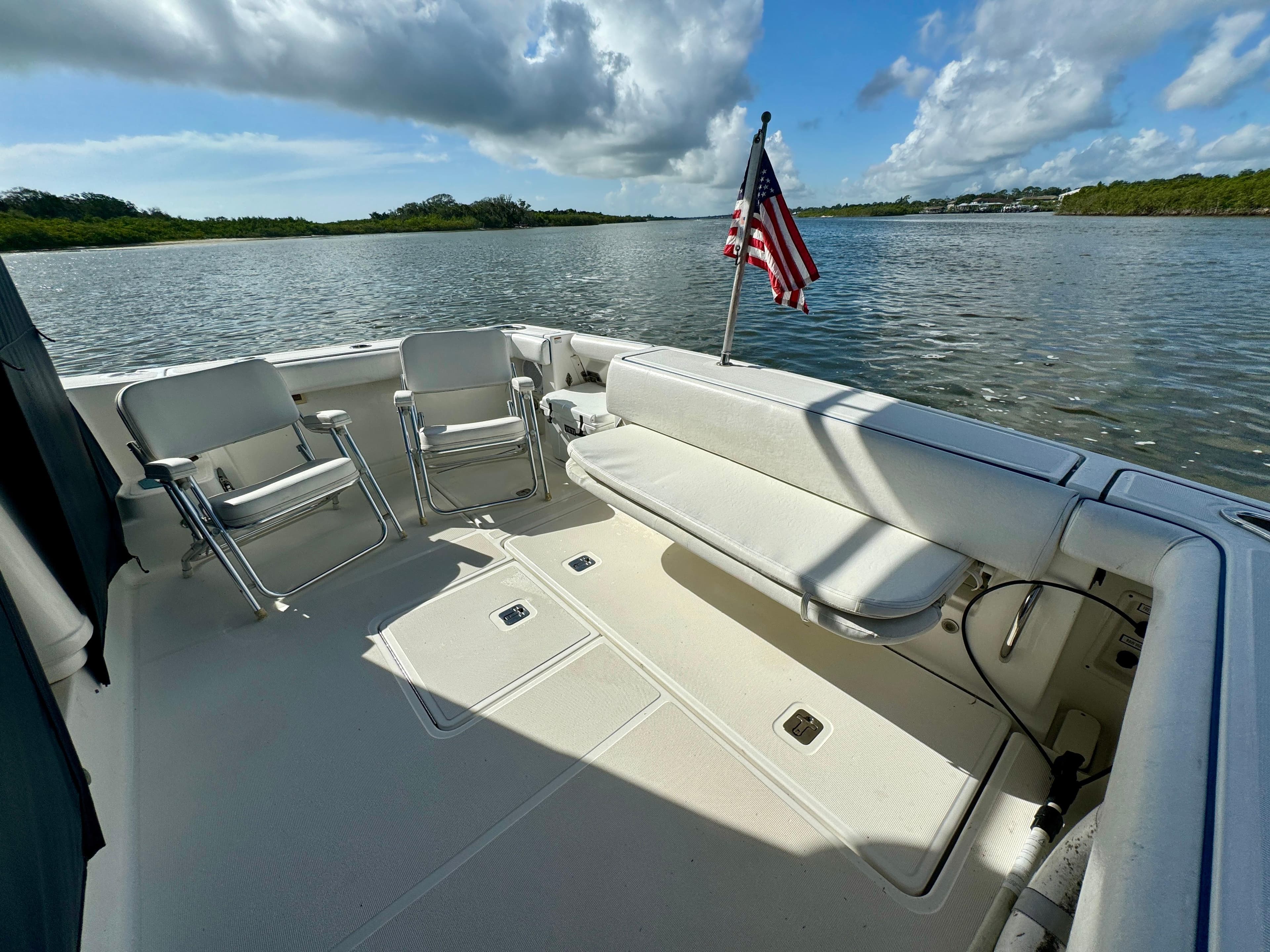 2006 Tiara Yachts 3200 Open boat deck with seating and American flag on calm water.