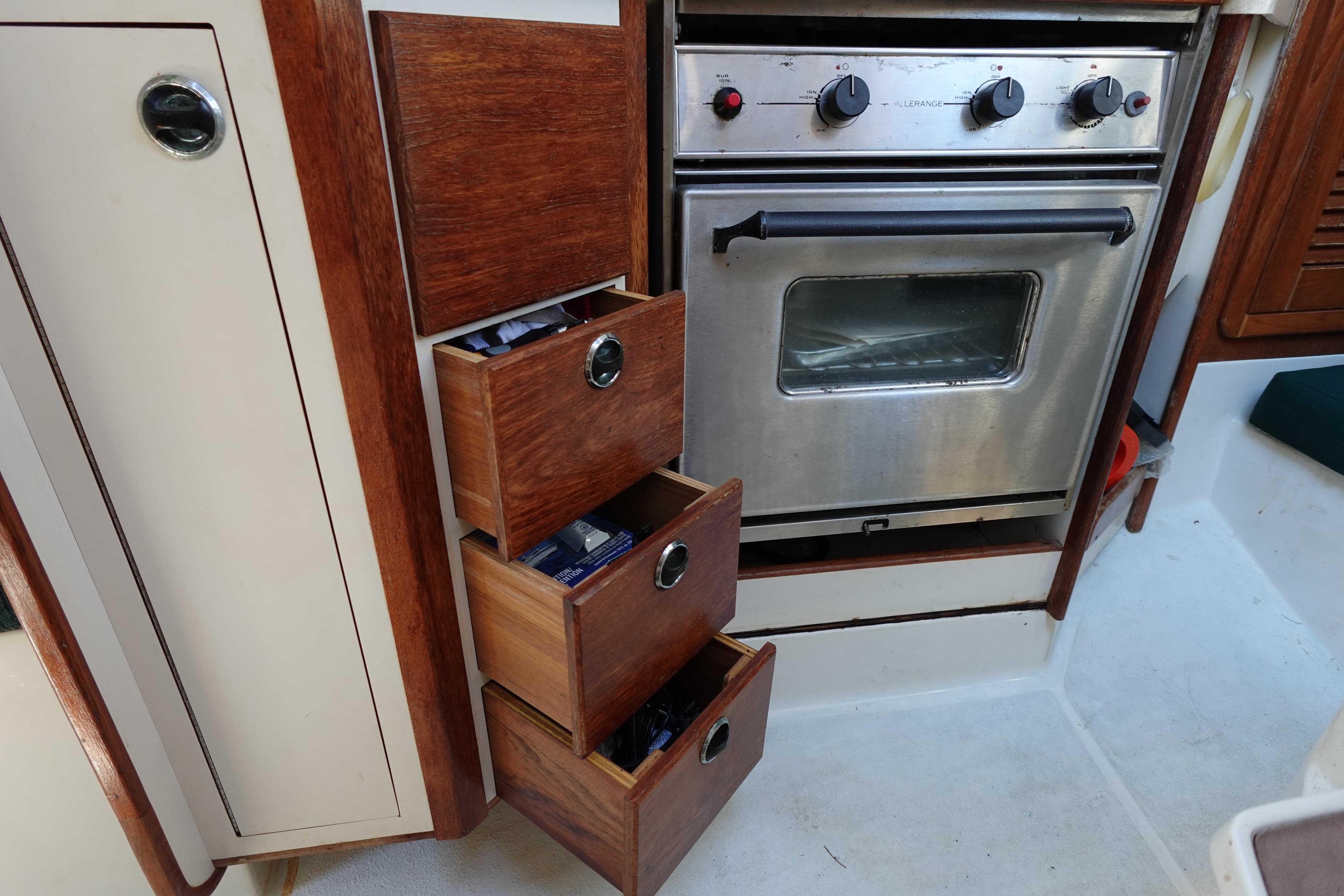 Interior of 1997 Catalina 28 sailboat with wooden drawers and stainless steel oven.