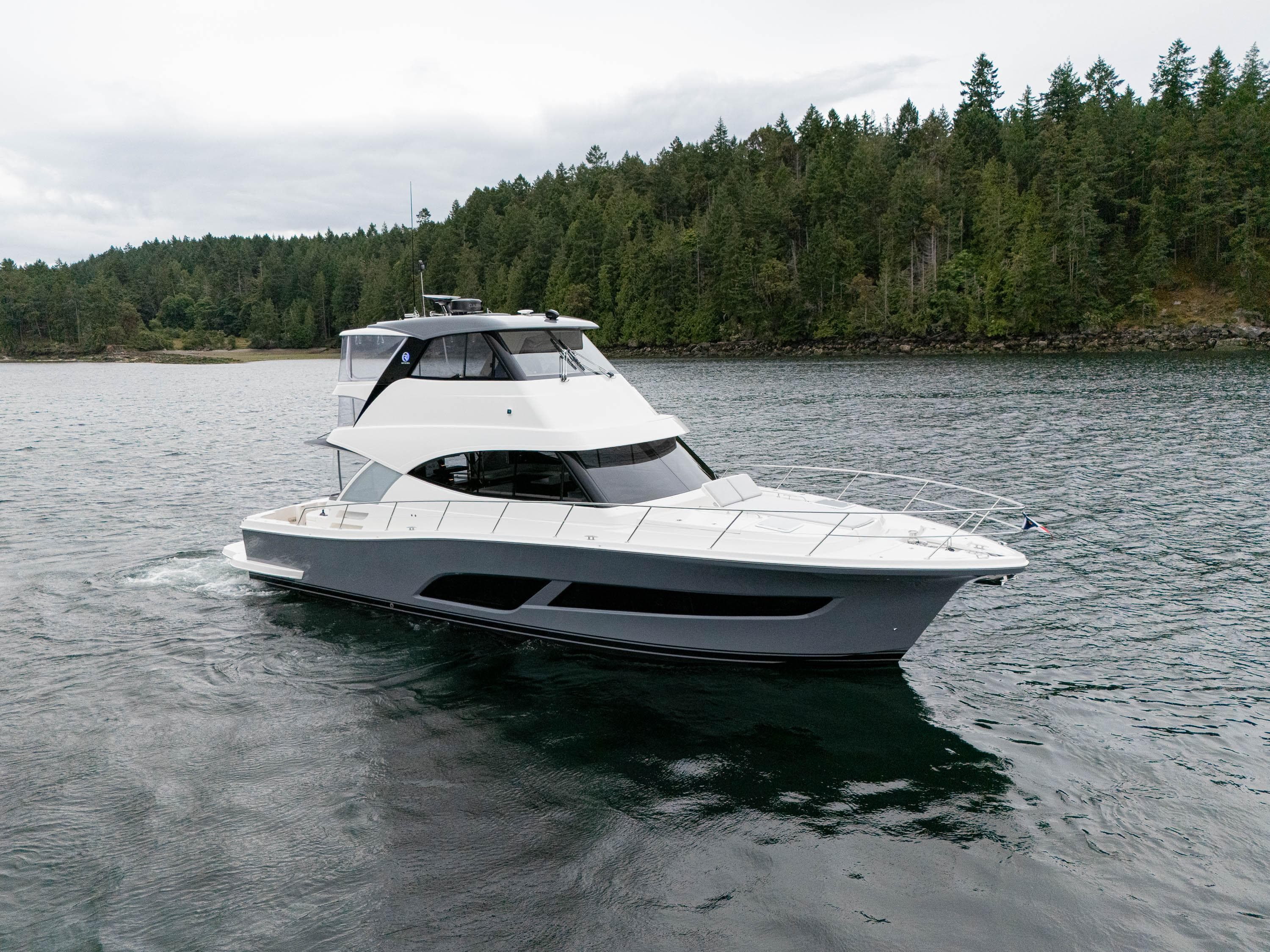 2025 Riviera 50 Sports Motor Yacht cruising on a serene lake with forested shoreline.