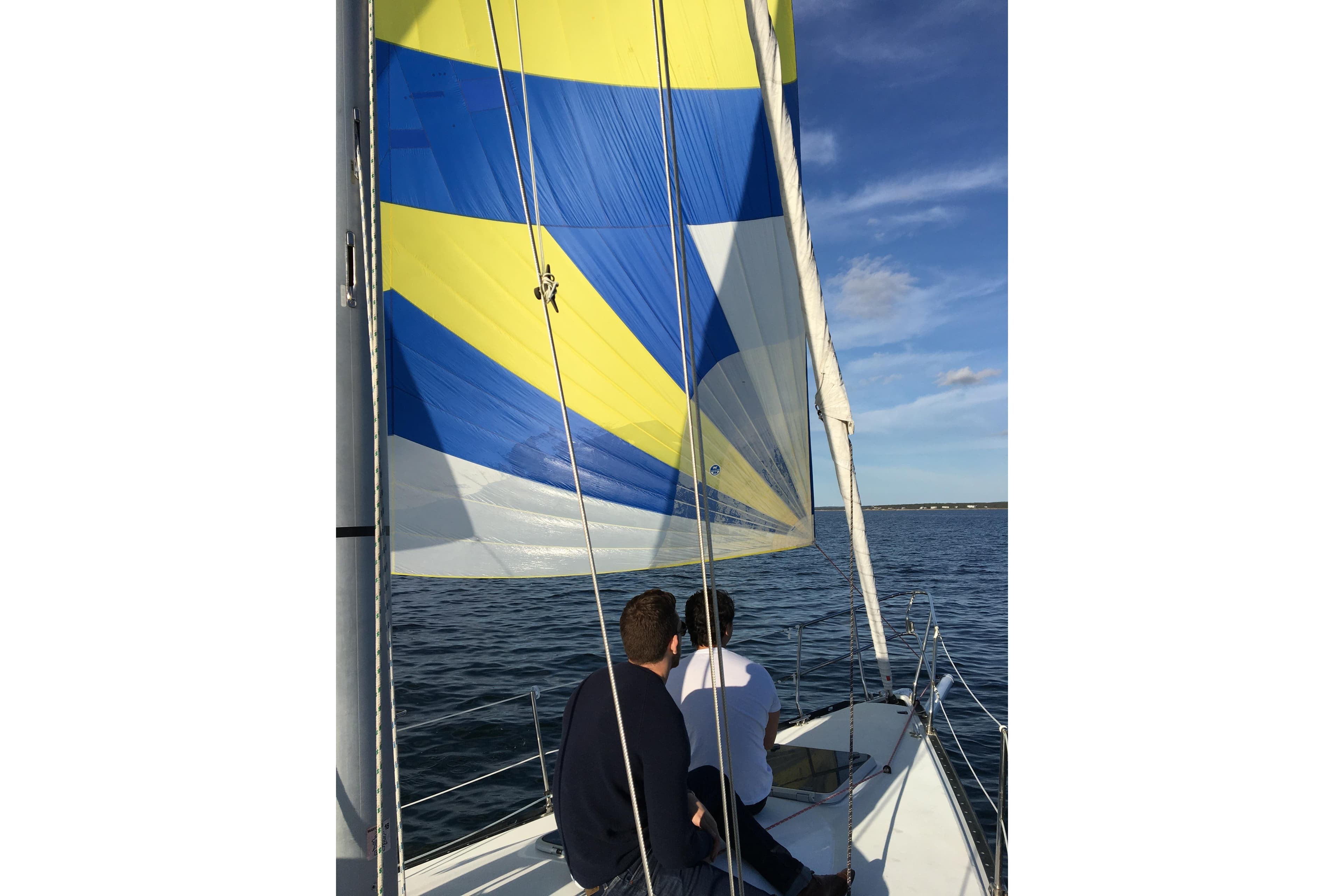 Two people sailing on a C&C 110 yacht with colorful sails.