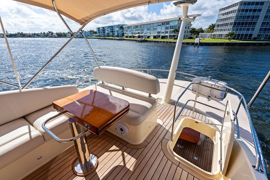 Luxurious 2018 Palm Beach PB55 Flybridge yacht with elegant seating and scenic waterfront view.