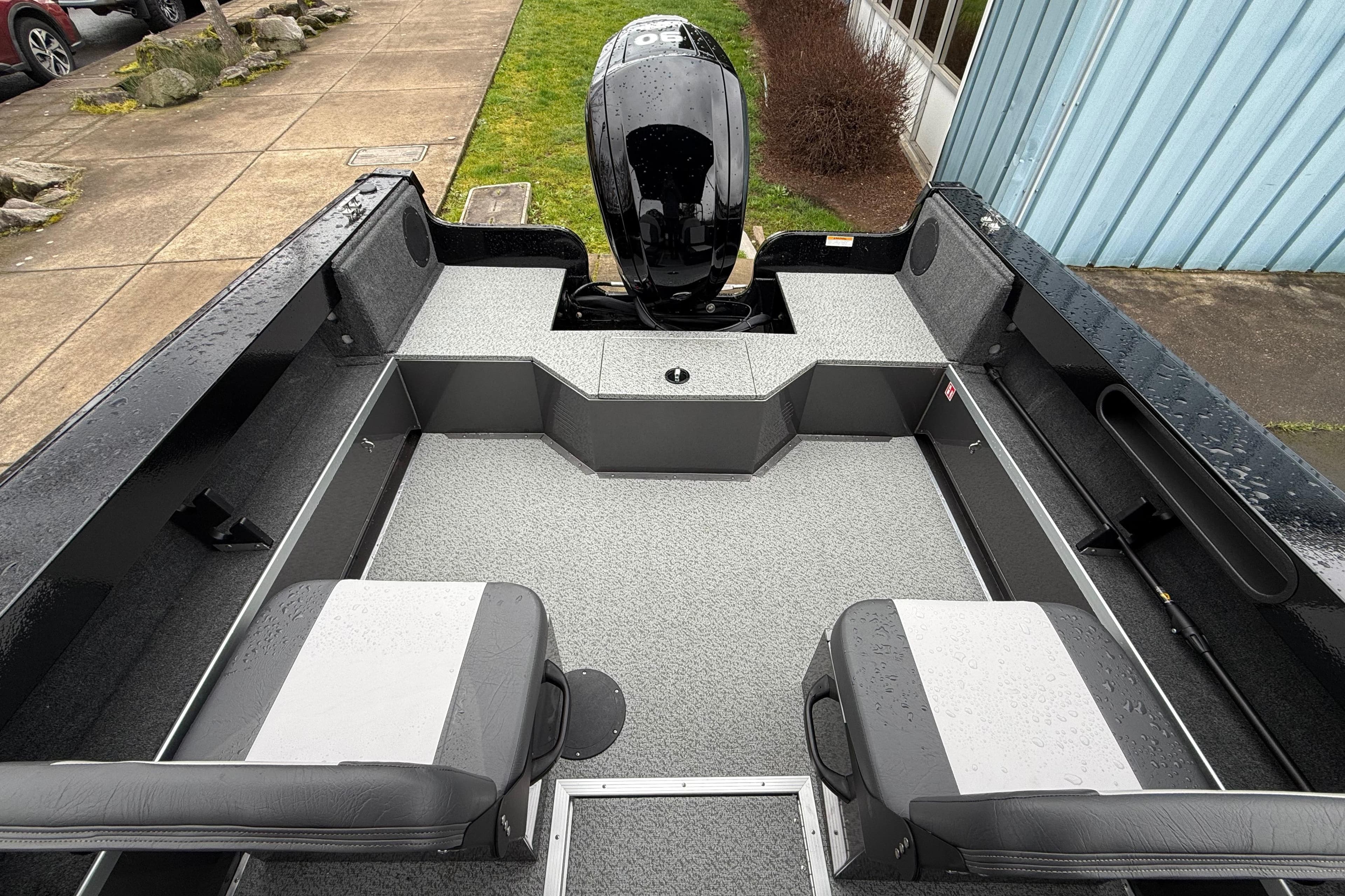 2026 Smoker Craft Osprey 172 boat interior with seating and motor, parked outdoors.