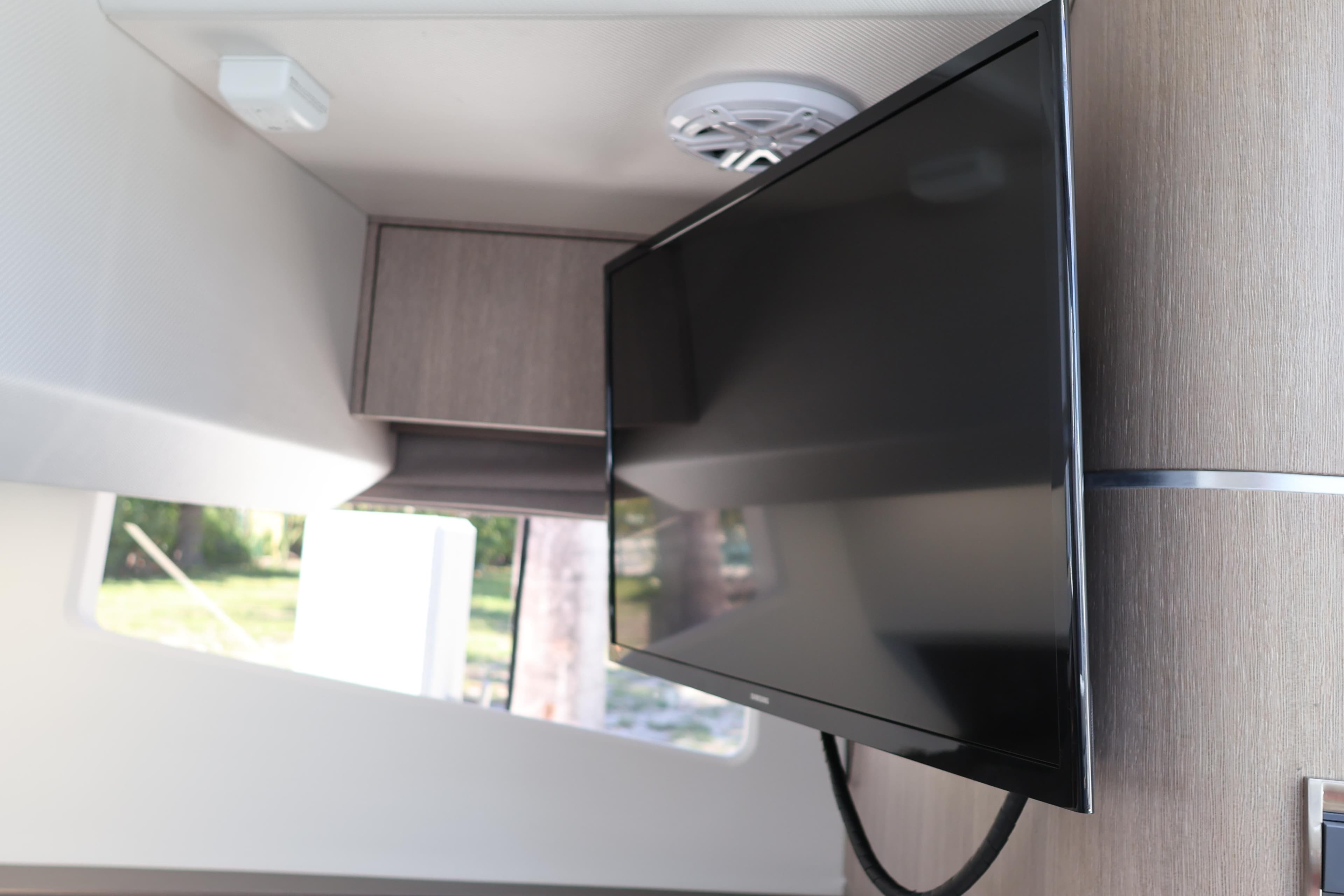 2024 Galeon 325 GTO interior with mounted flat-screen TV and modern wood paneling.