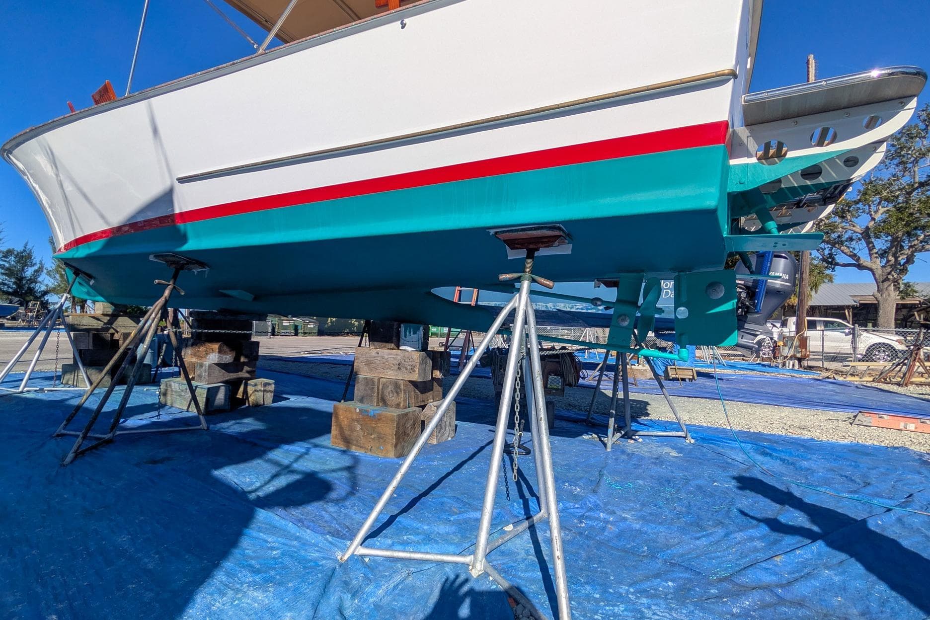1954 Daniels Brothers 28 boat on stands, vibrant teal and white hull, outdoor setting.