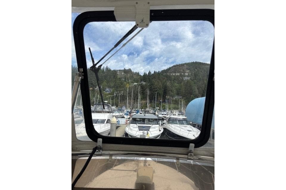 View from 2004 Canoe Cove Sedan, overlooking marina with boats and forested hills.