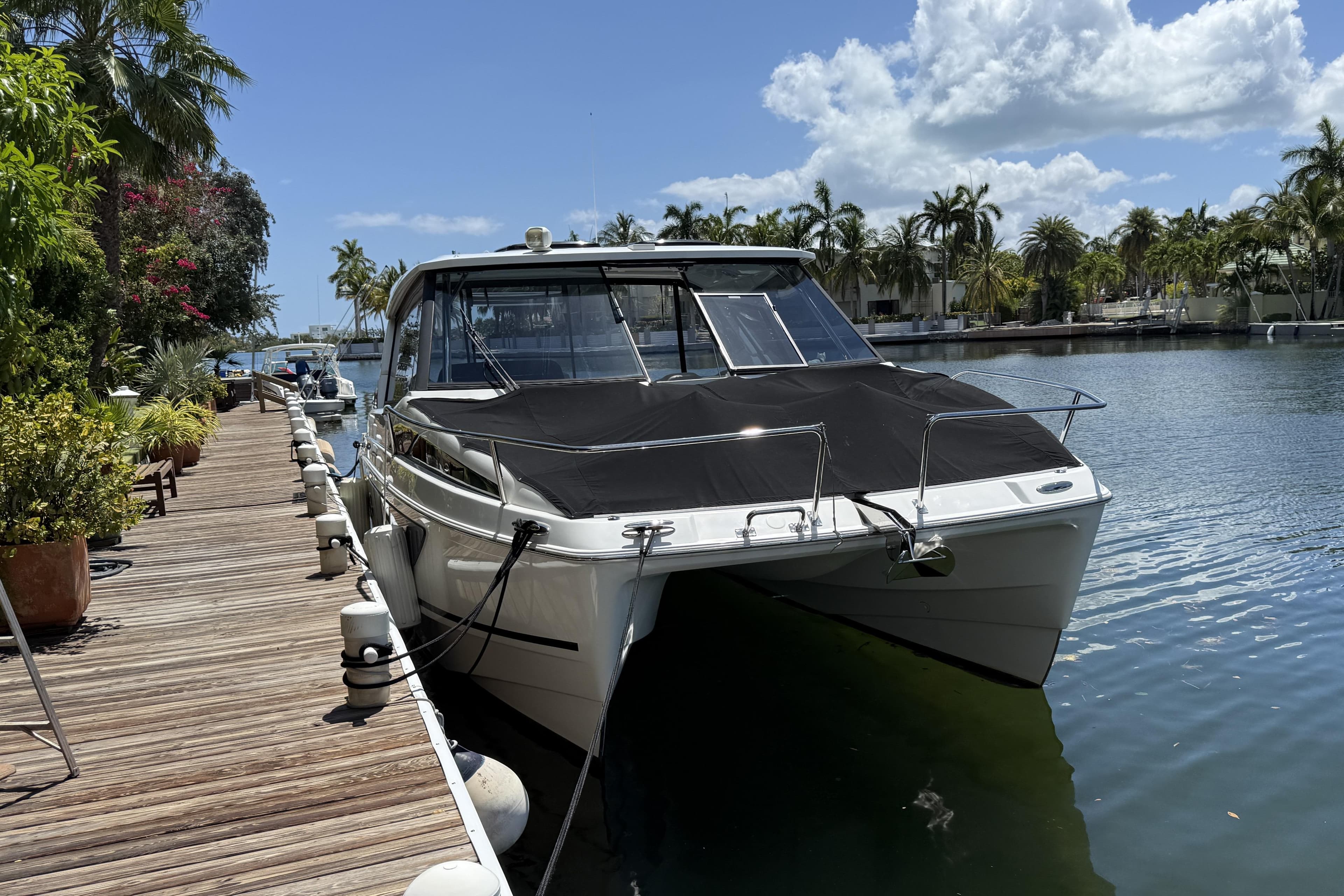2021 Aquila 36 Sport boat docked by a scenic waterfront with palm trees.