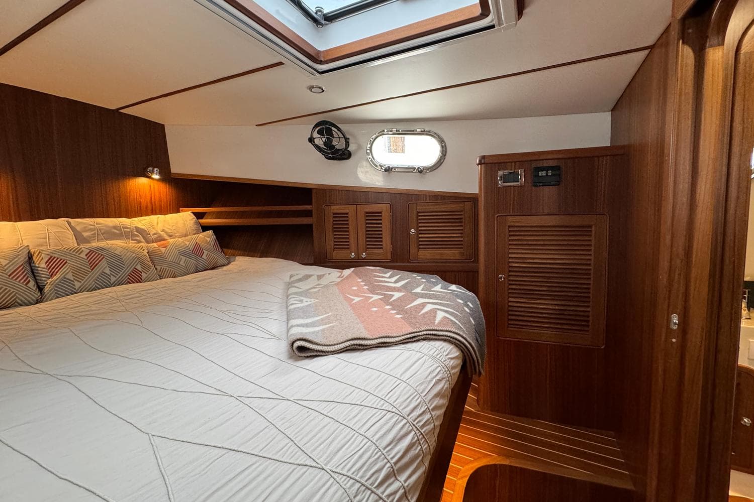 Luxurious cabin interior of 2026 Helmsman Trawlers 38 Sedan with wood finish and cozy bedding.