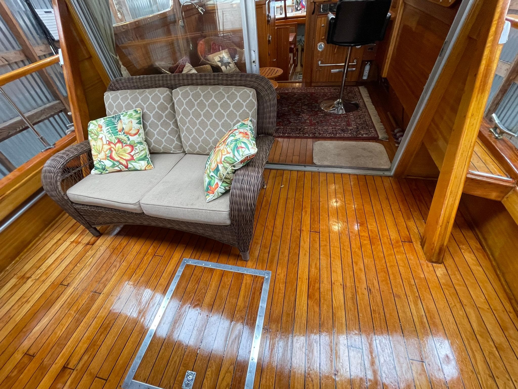 1959 Monk Express Cruiser interior with polished wood floor, wicker sofa, and floral cushions.