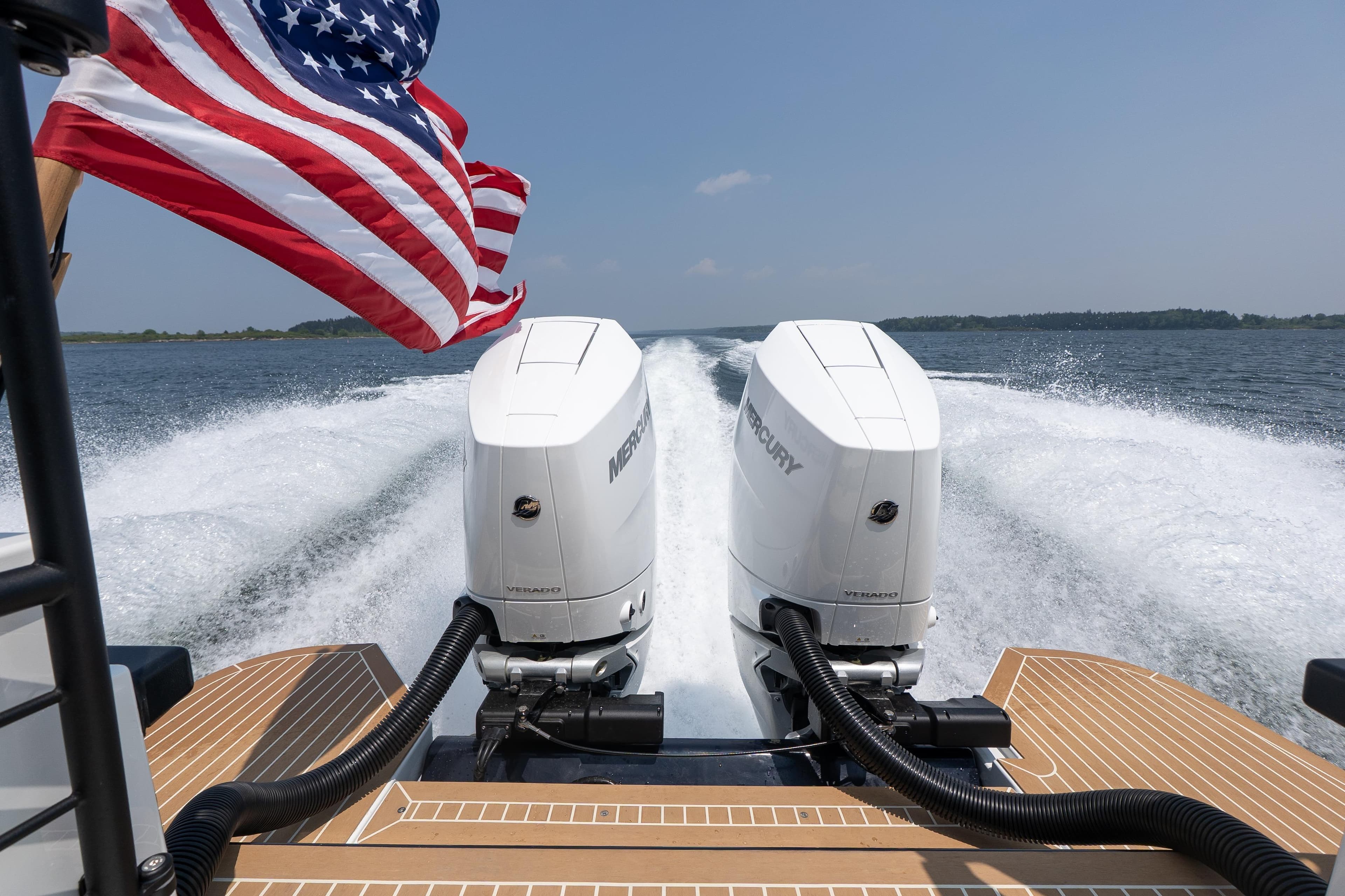 2027 Targa 32 OB boat with dual Mercury outboard engines, American flag waving, cruising on open water.