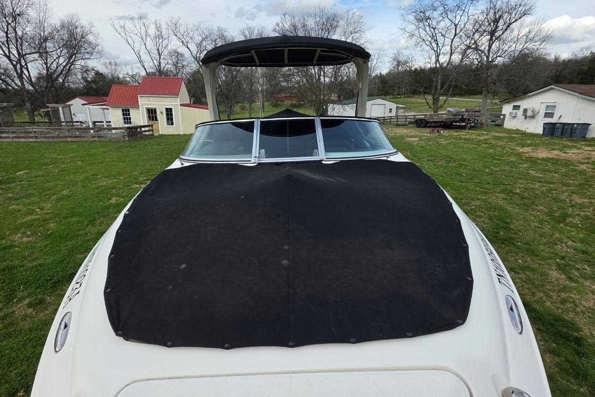 2011 Sea Ray SLX 250 boat with black cover on grassy area.