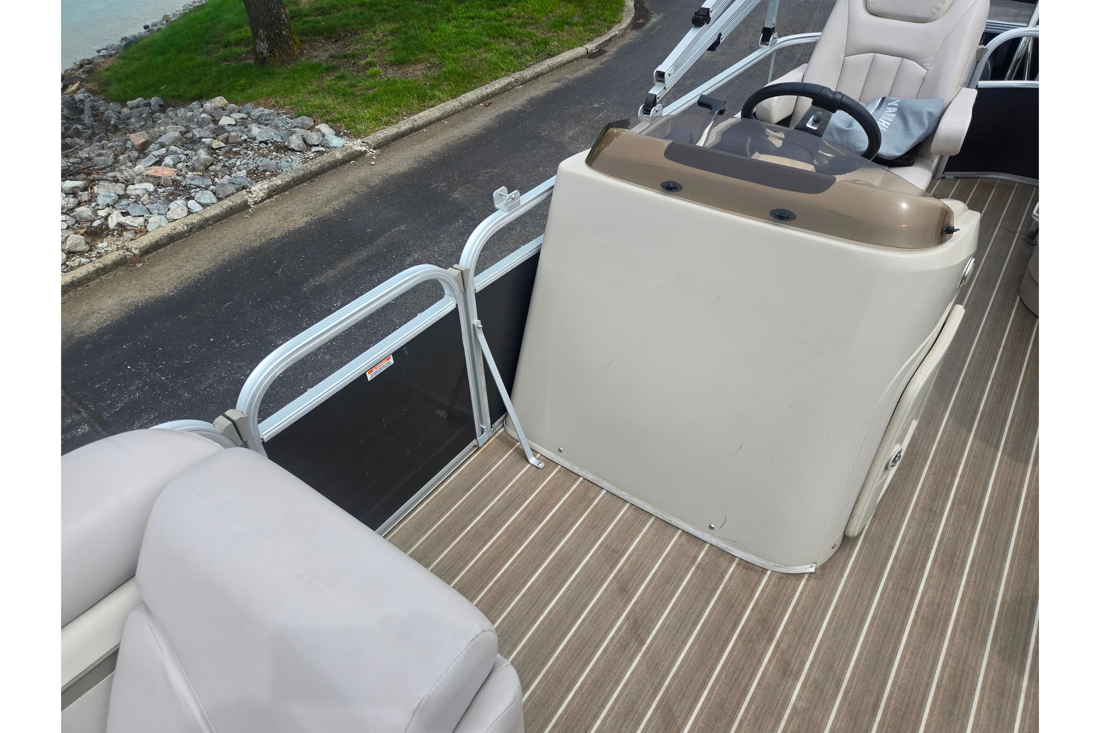 2014 Bennington 22 SLX boat interior with steering console and seating, docked by a rocky shoreline.