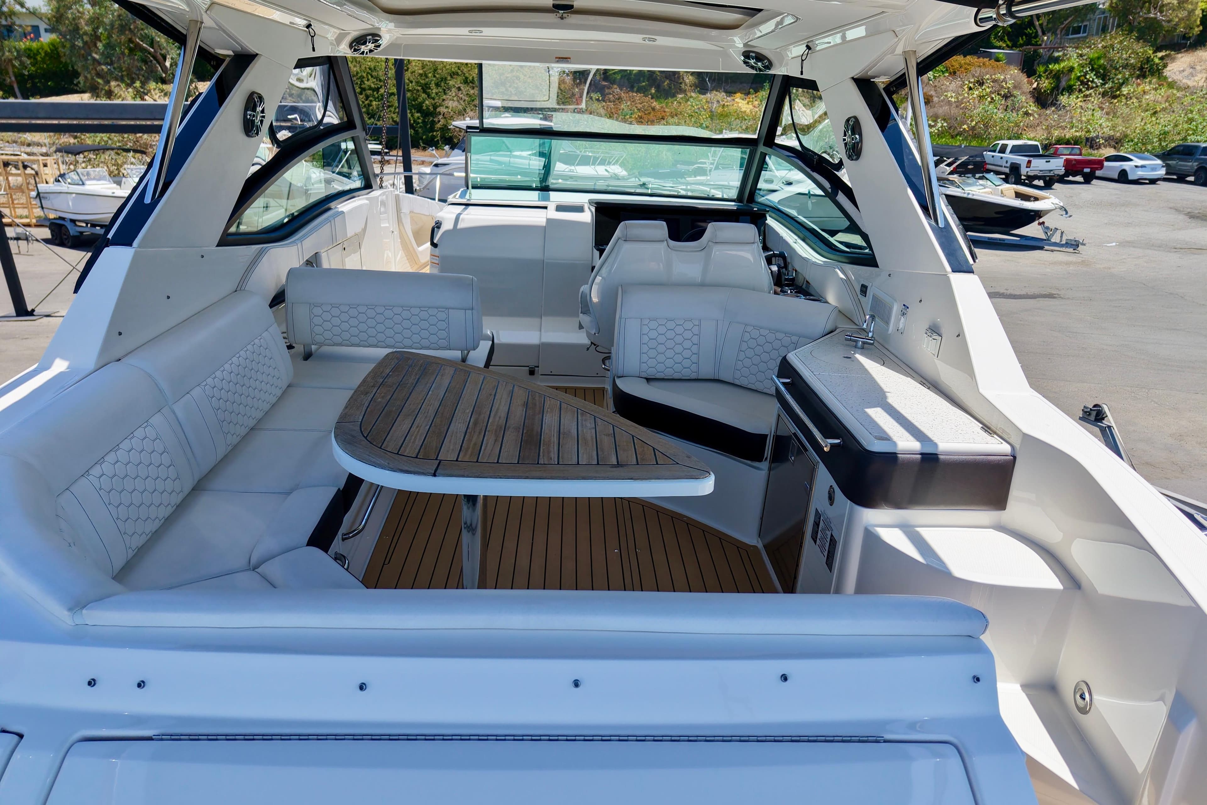 2019 Sea Ray Sundancer 320 interior with seating, table, and helm in a marina setting.