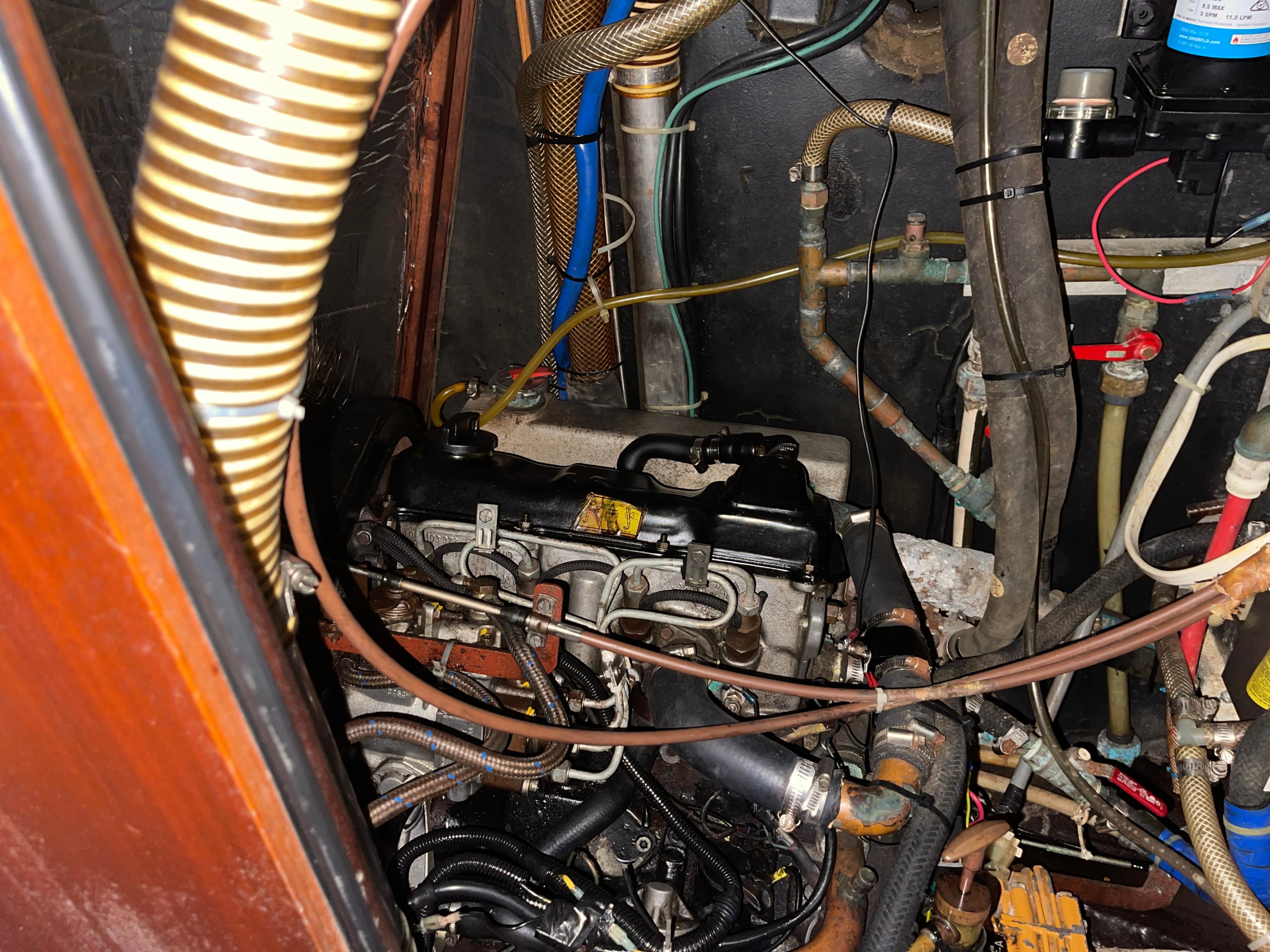 Engine compartment of a 1984 Hanseat 37 sailboat, showcasing various hoses and components.