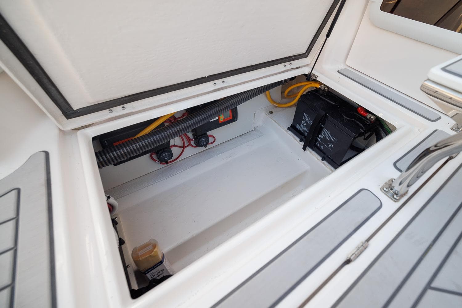 Open storage compartment in 2026 Solara S-310 SB boat, showing battery and wiring.