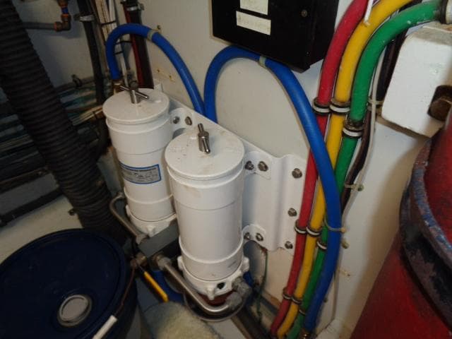 Engine room of 1989 Hatteras 67 Cockpit Motor Yacht with filters and colorful wiring.
