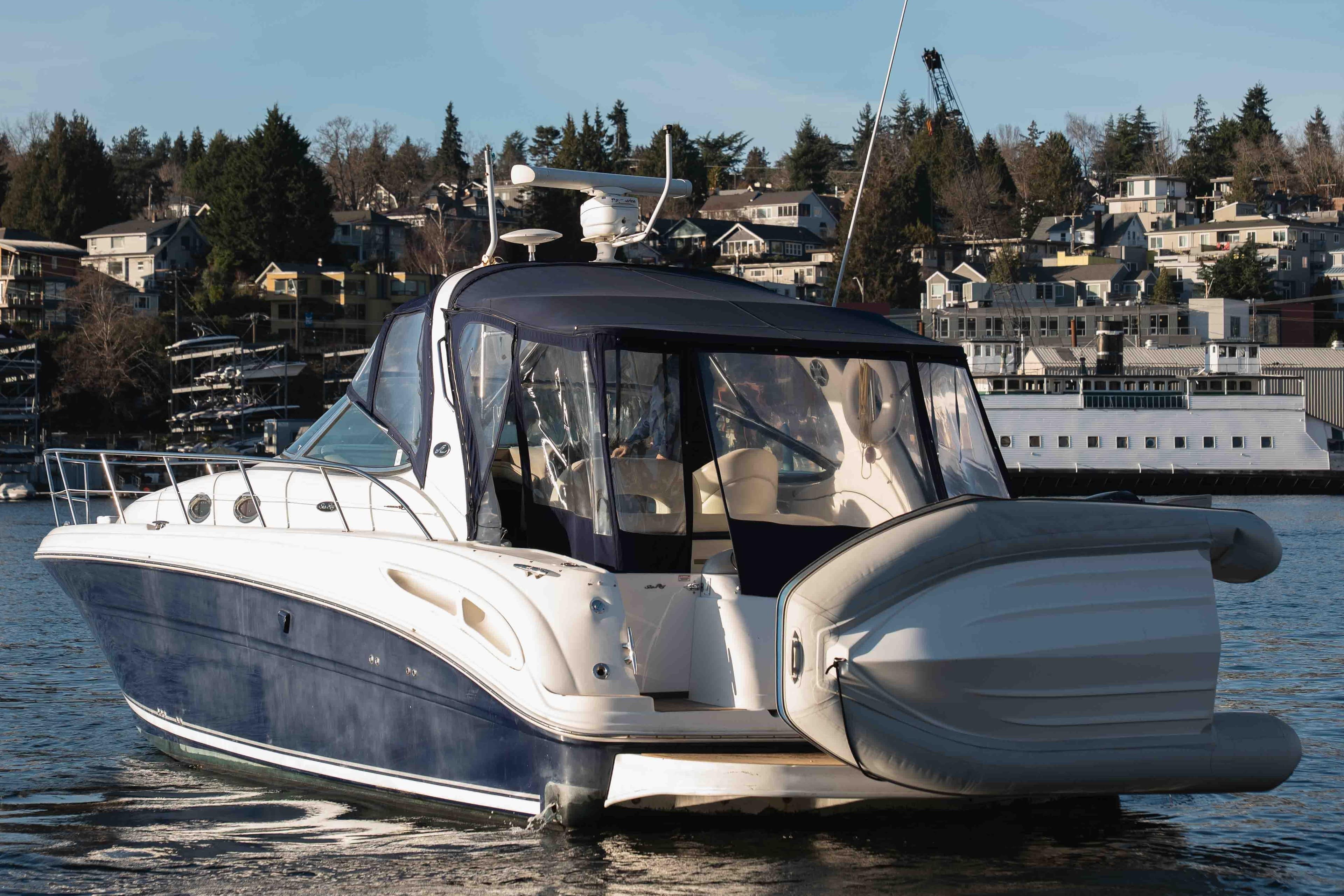 2004 Sea Ray 360 Sundancer yacht with inflatable boat, docked near waterfront homes.
