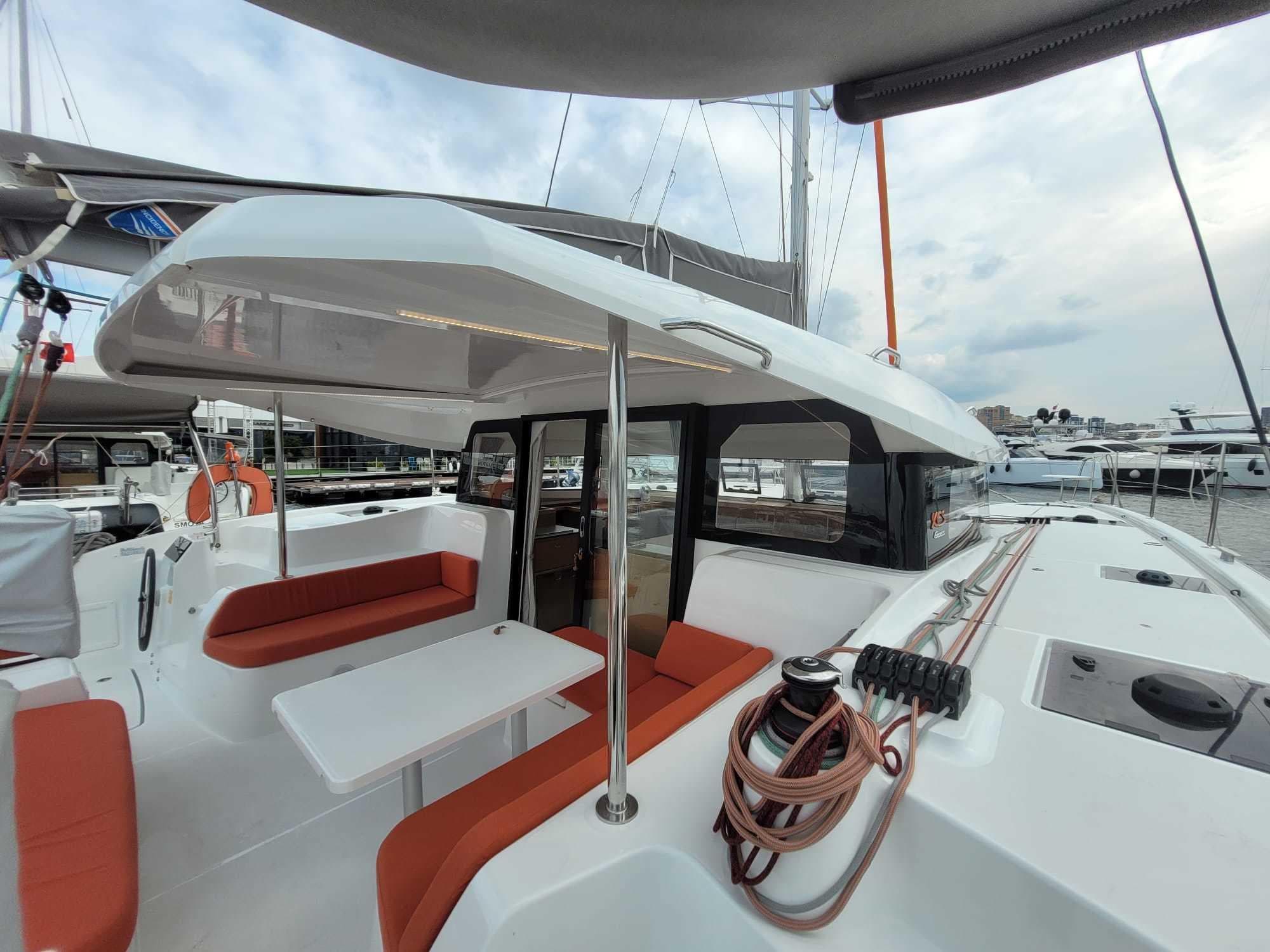 2023 Excess 11 catamaran with orange seating, docked at a marina under cloudy skies.