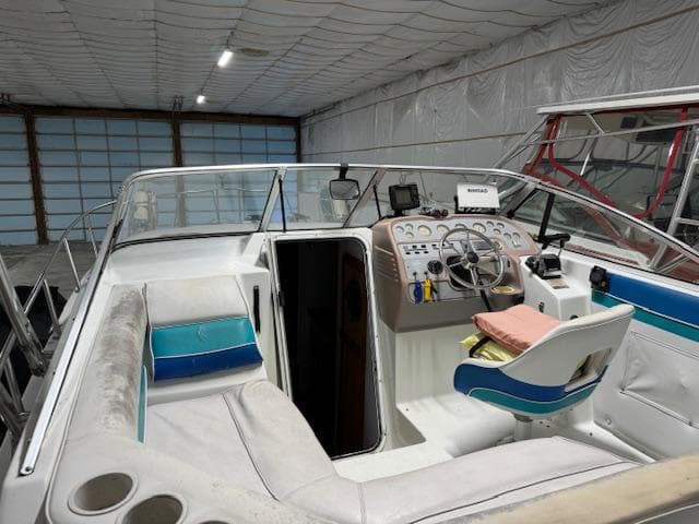 1993 Rinker 280 Fiesta Vee boat interior with steering wheel and seating in a storage facility.