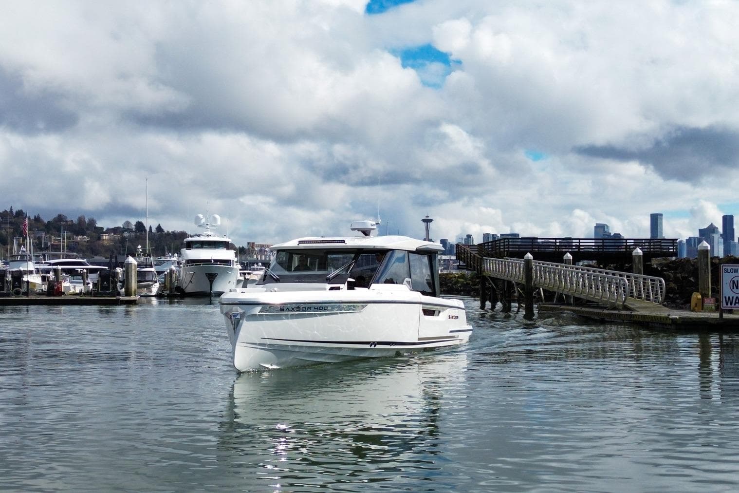 2026 Saxdor 400 GTC boat cruising in a marina with city skyline backdrop.