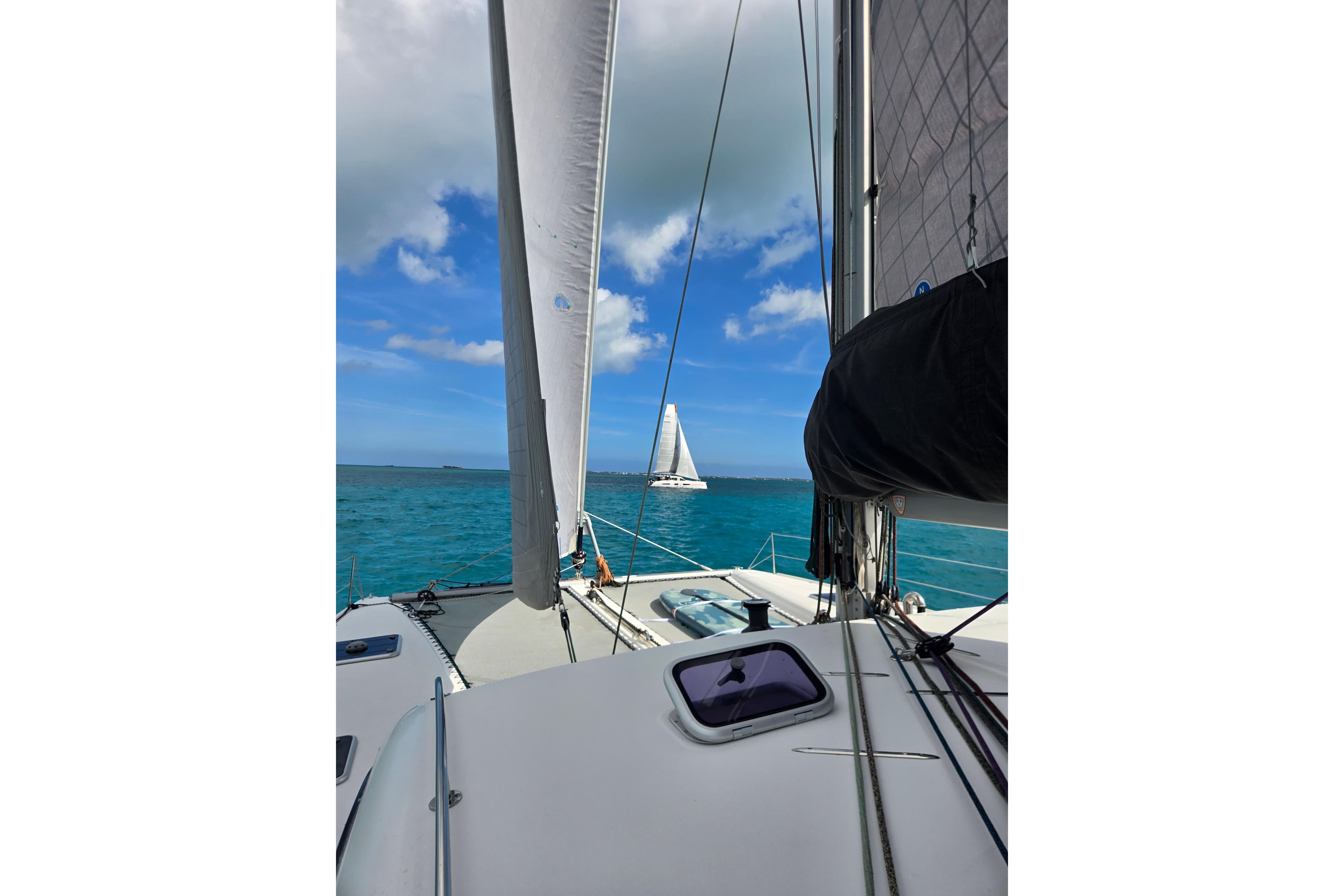 Sailing on a 2016 Outremer 45 catamaran in clear blue waters under a sunny sky.