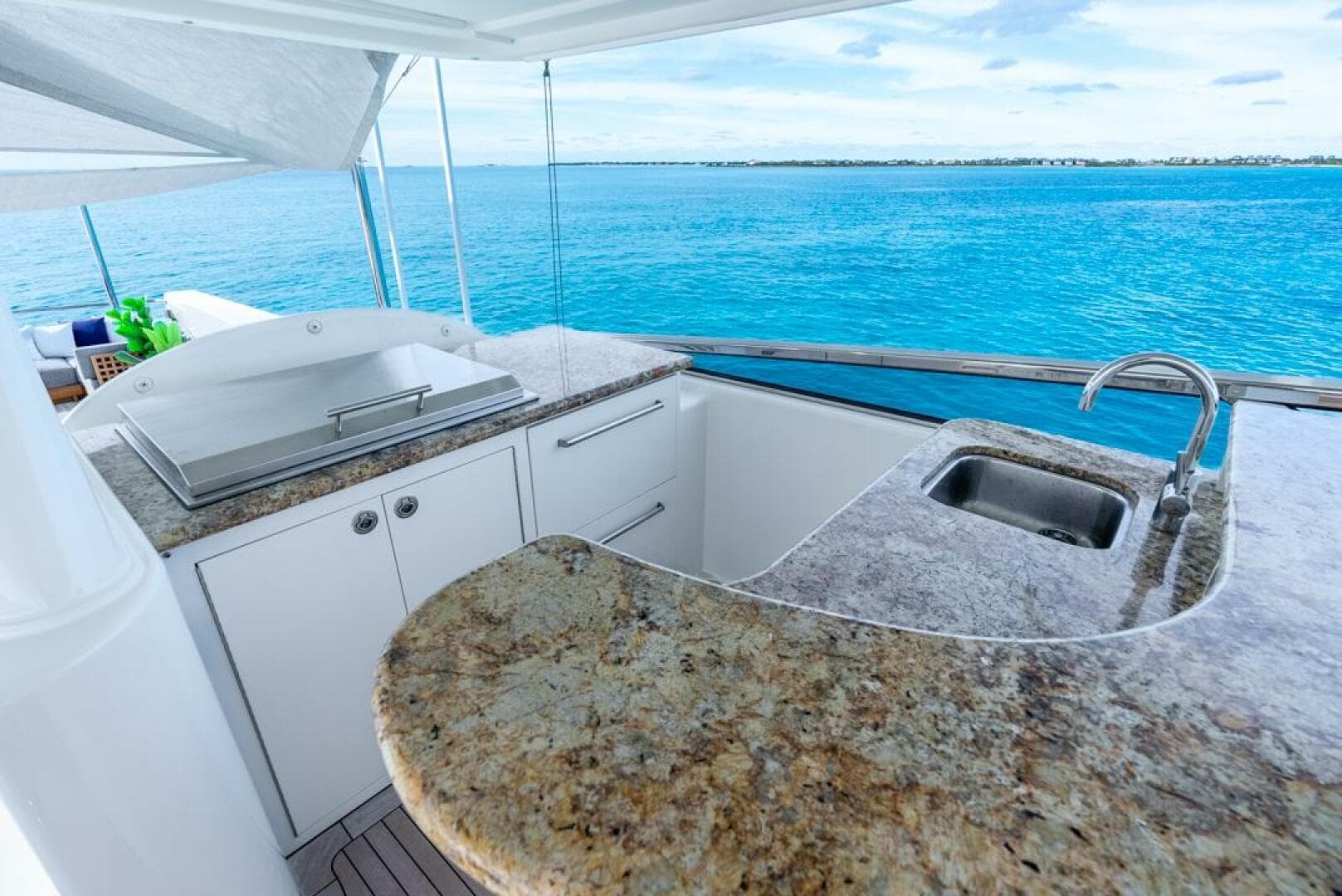 Luxurious Westport 112 yacht kitchen with granite countertops, overlooking serene blue ocean waters.