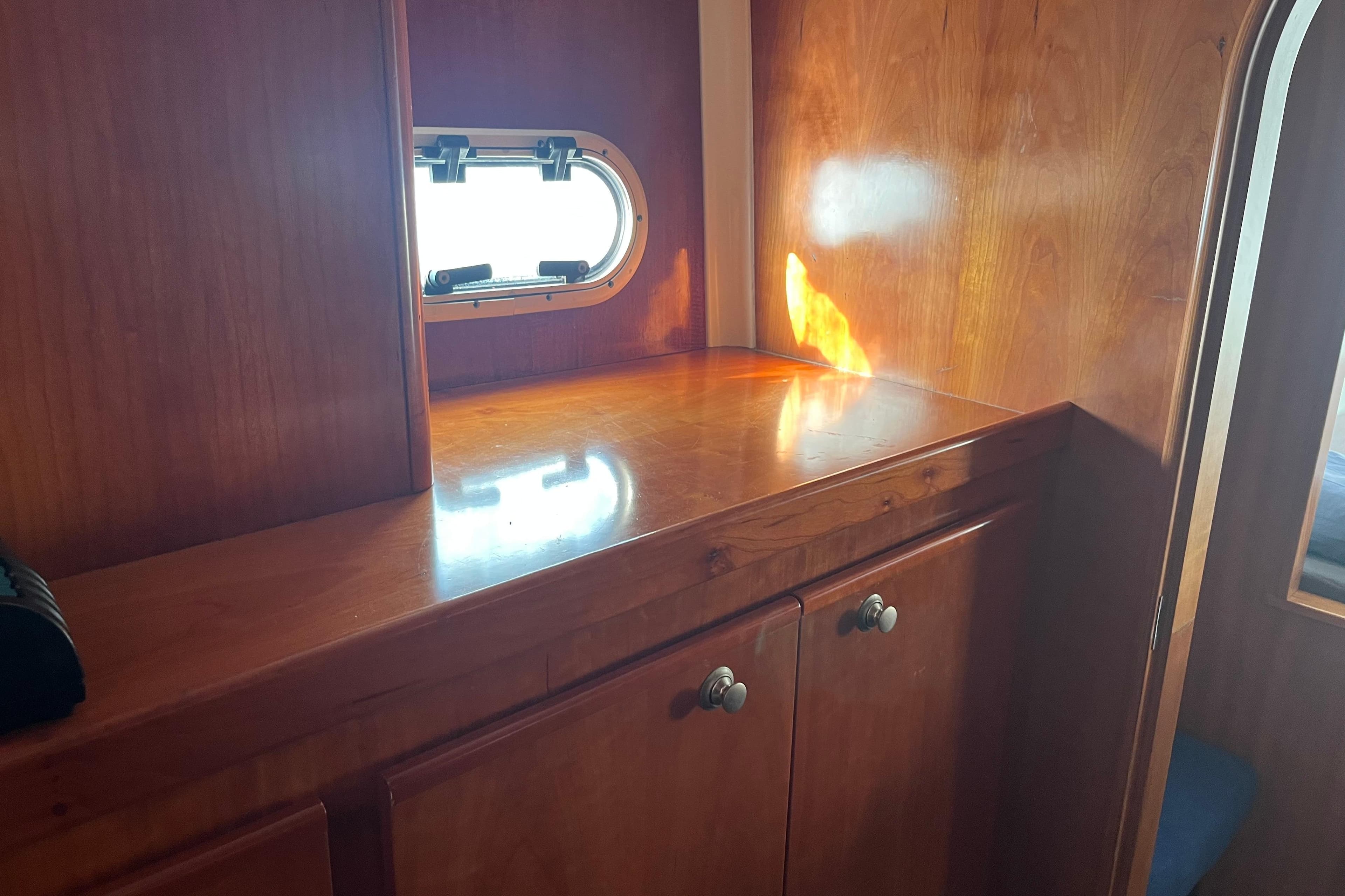 Interior of 2004 Catana 471 Ocean Class, featuring wooden cabinetry and a small window.
