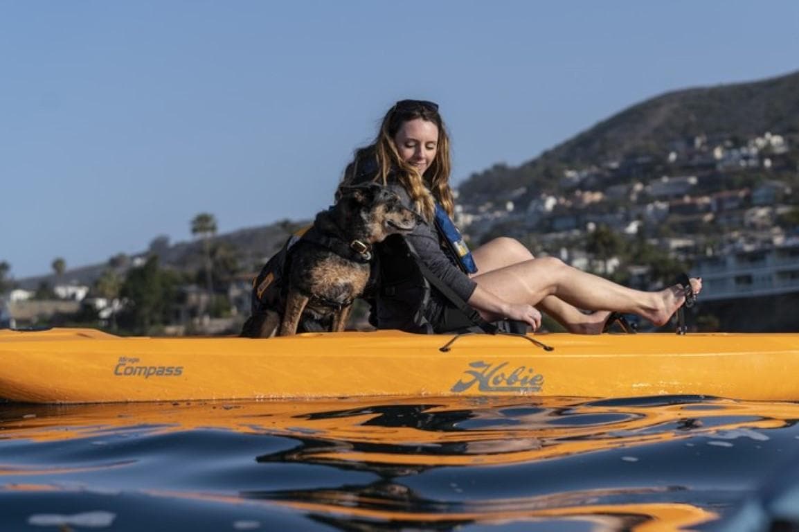 Woman and dog kayaking on a 2023 Hobie Compass in scenic waters.
