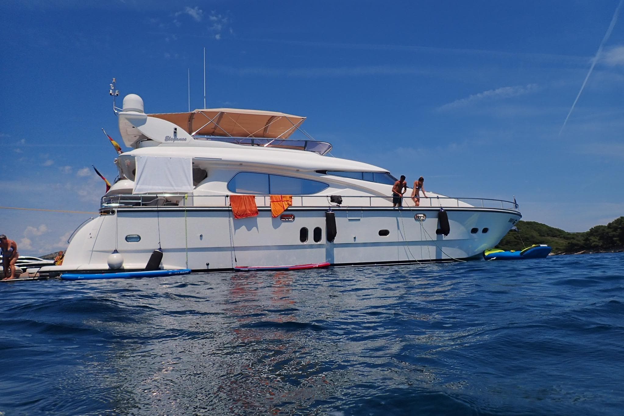 Luxury yacht Elegance 64, 2007 model, anchored on a sunny day with people on deck.