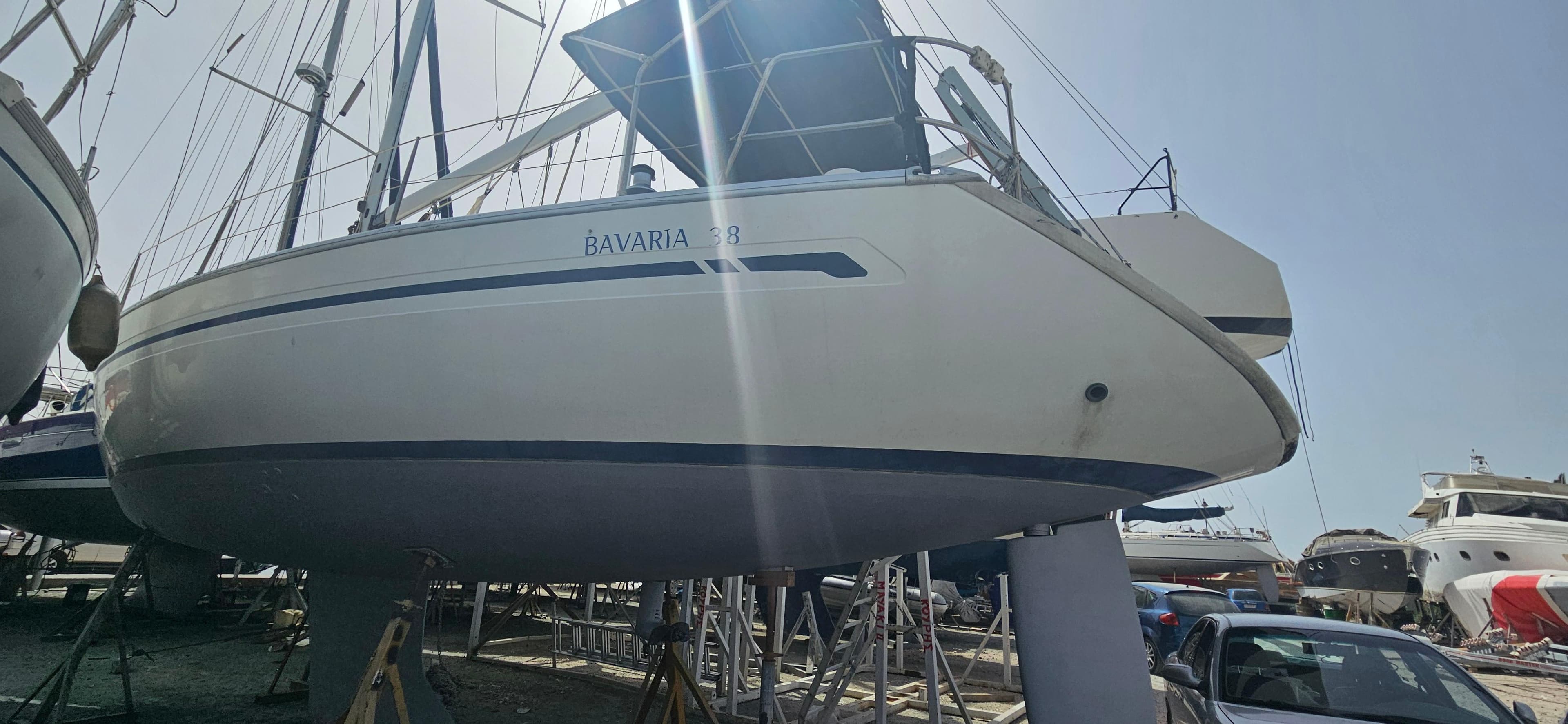 2004 Bavaria 38 sailboat on dry dock, side view under bright sunlight.