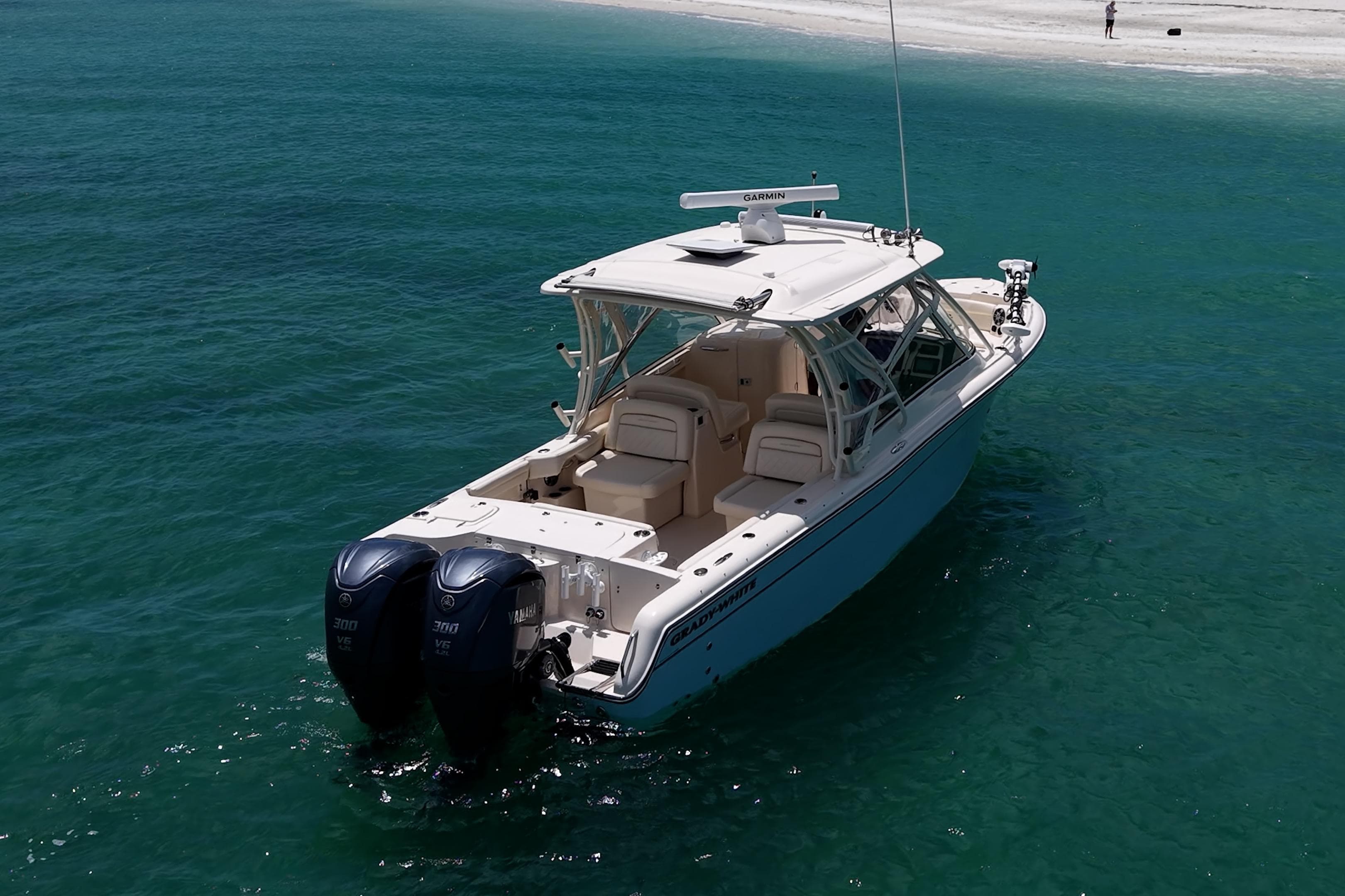 2022 Grady-White Freedom 285 boat on clear turquoise water near sandy beach.