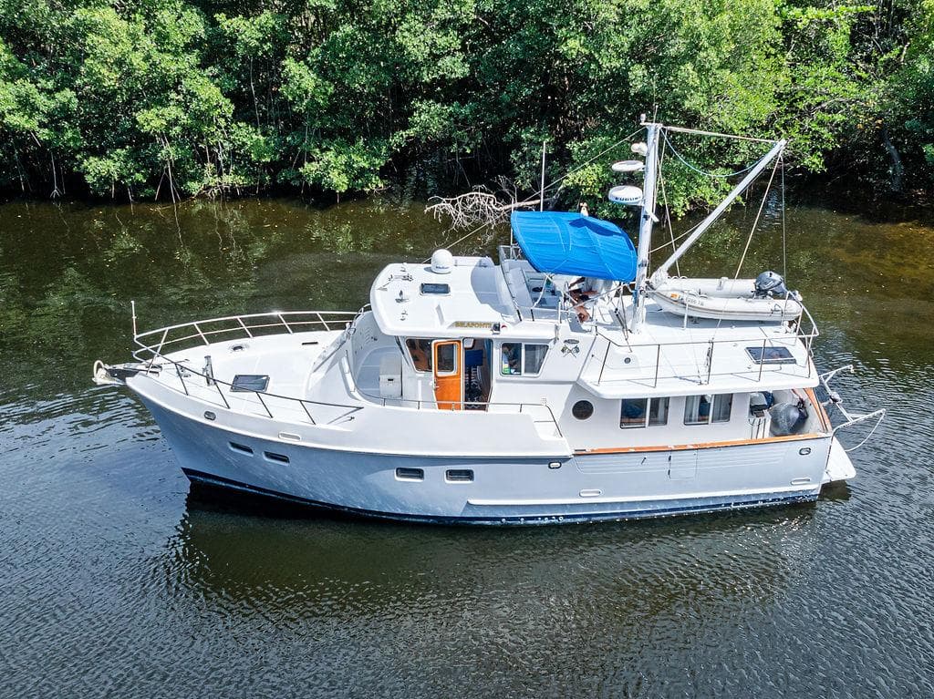 Selene Solo 2000 yacht cruising on a calm river, surrounded by lush greenery.