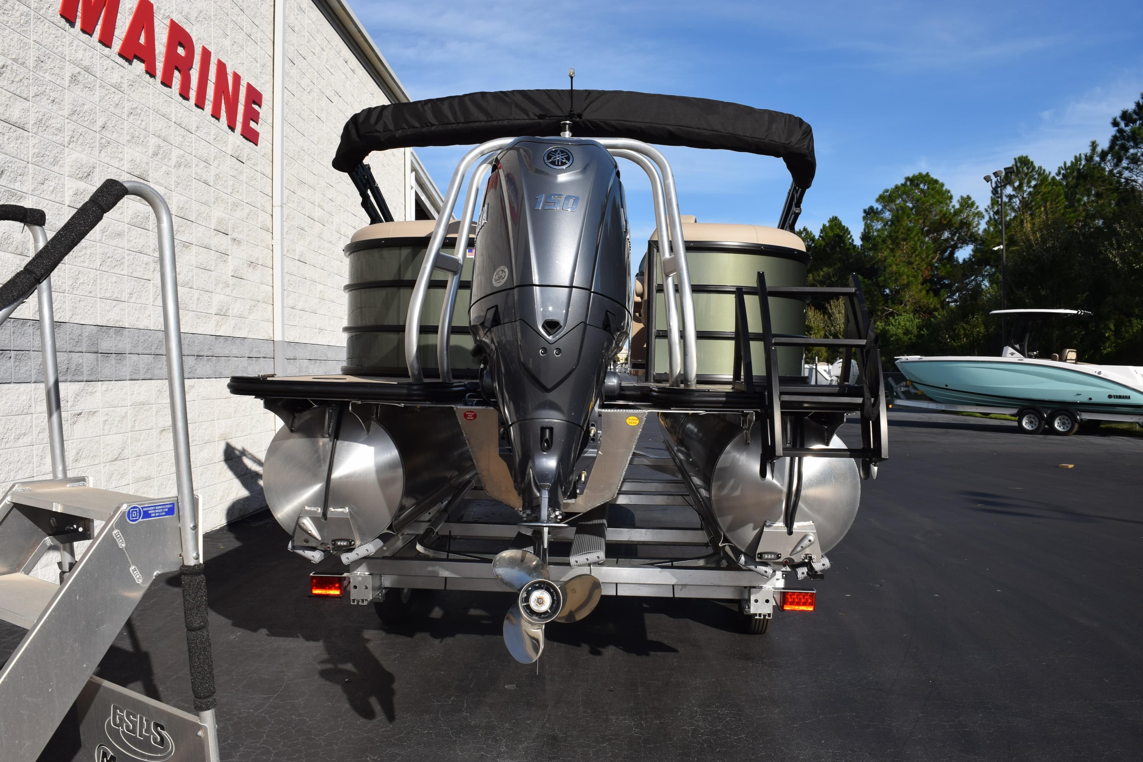 2026 Bentley Pontoons Legacy 223 Navigator with outboard motor, parked at a marine dealership.