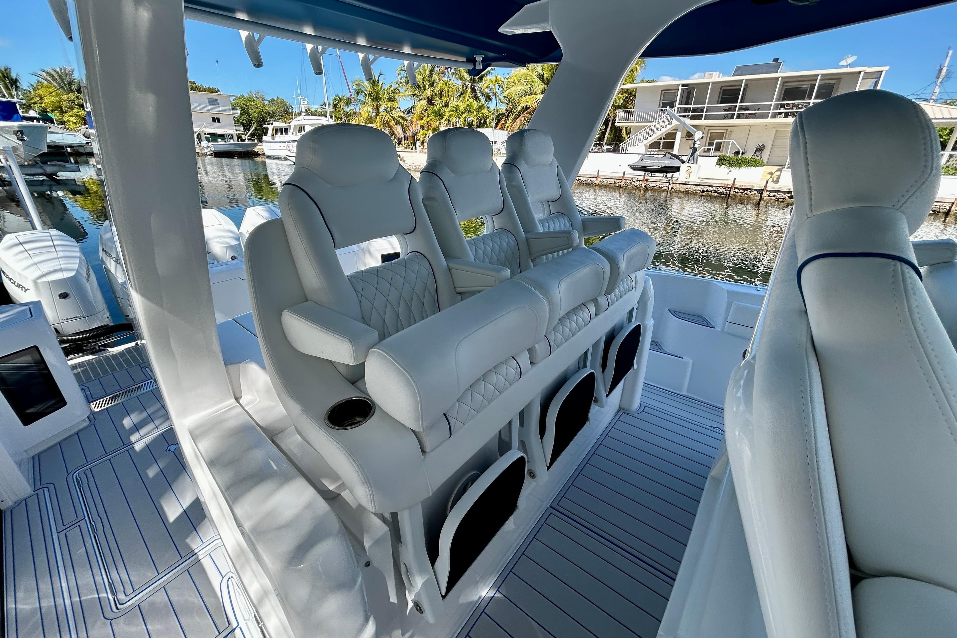 Luxurious seating on 2025 Intrepid 43 Nomad SE boat, docked by waterfront homes.