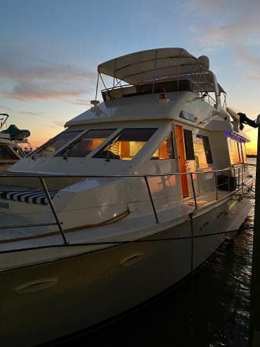 1990 Viking Extended Aft Deck Motor Yacht at sunset, docked with illuminated interior.