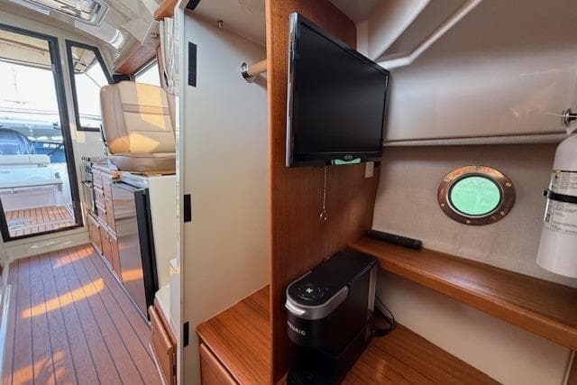 Interior of 2023 Ranger Tugs R-27 boat with TV, porthole, and wooden cabinetry.