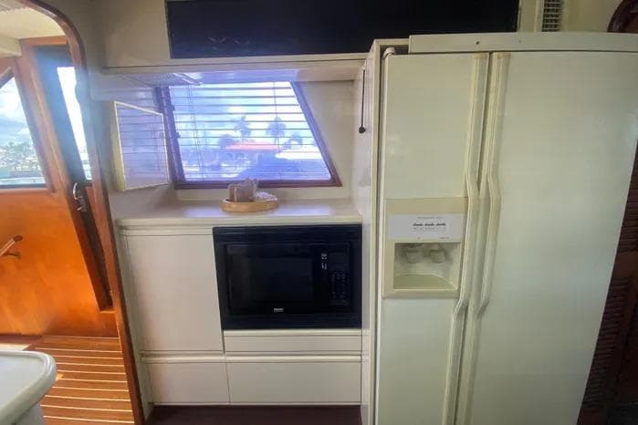 Interior of 1990 Viking Motor Yacht kitchen with fridge, microwave, and window view.