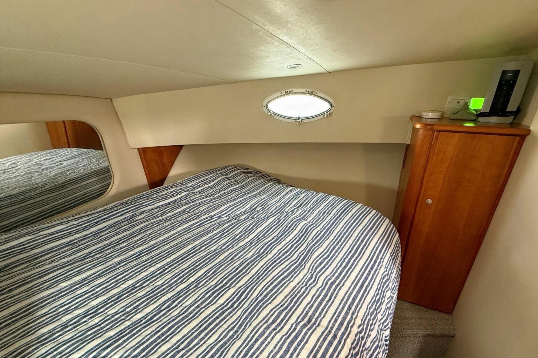 1999 Silverton 392 Motor Yacht bedroom with striped bedding and wooden cabinetry.