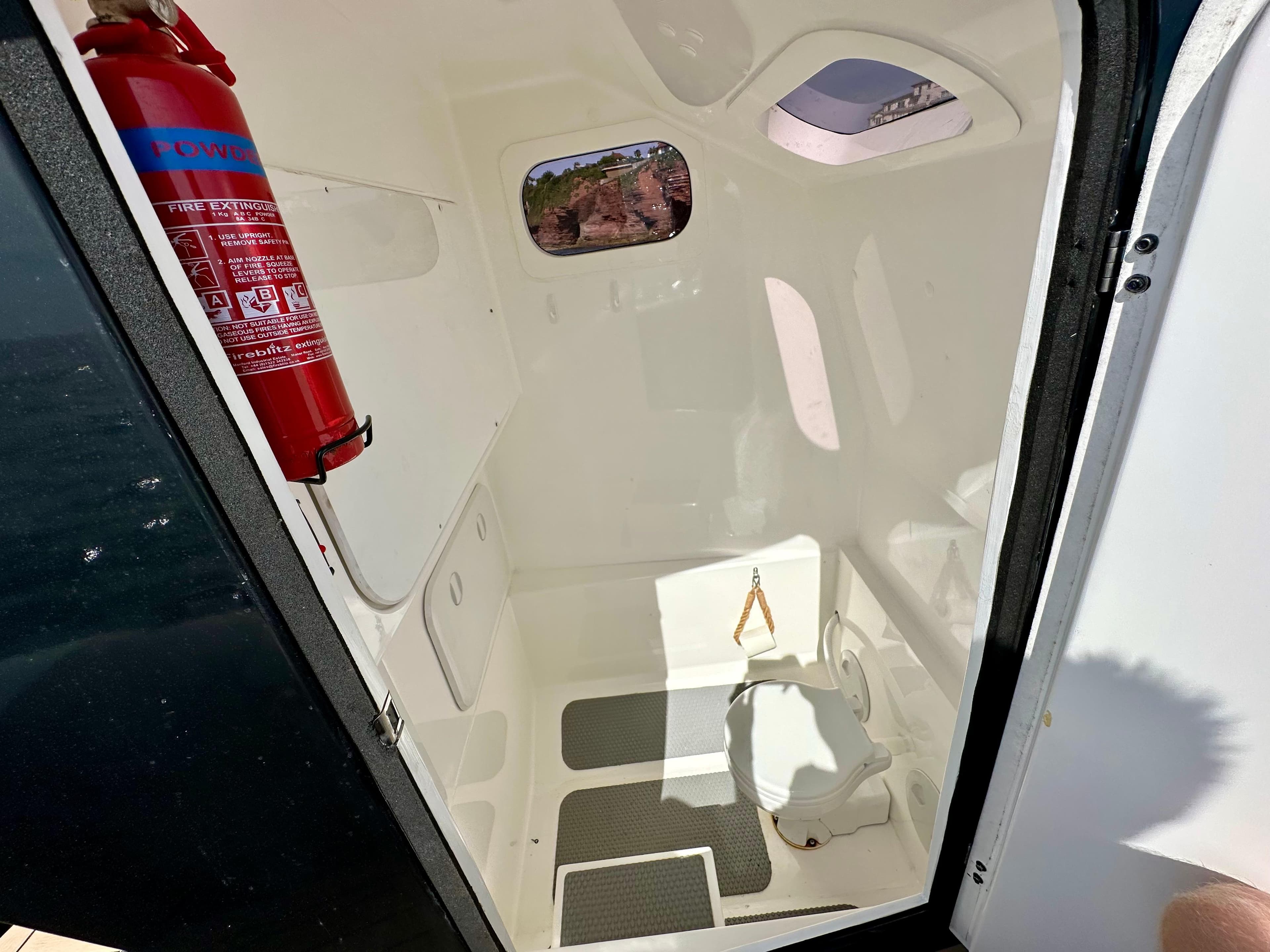 Interior of 2021 Ribquest Explorer boat with fire extinguisher and toilet.