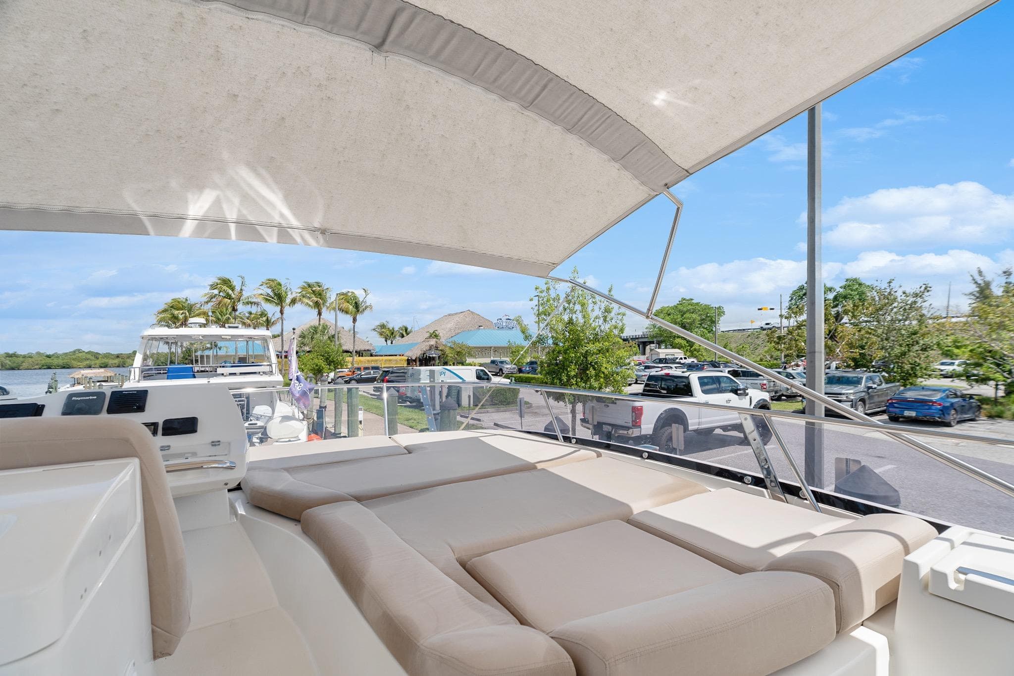 Luxurious 2016 Prestige 500 yacht with spacious deck, docked near palm trees and parked cars.