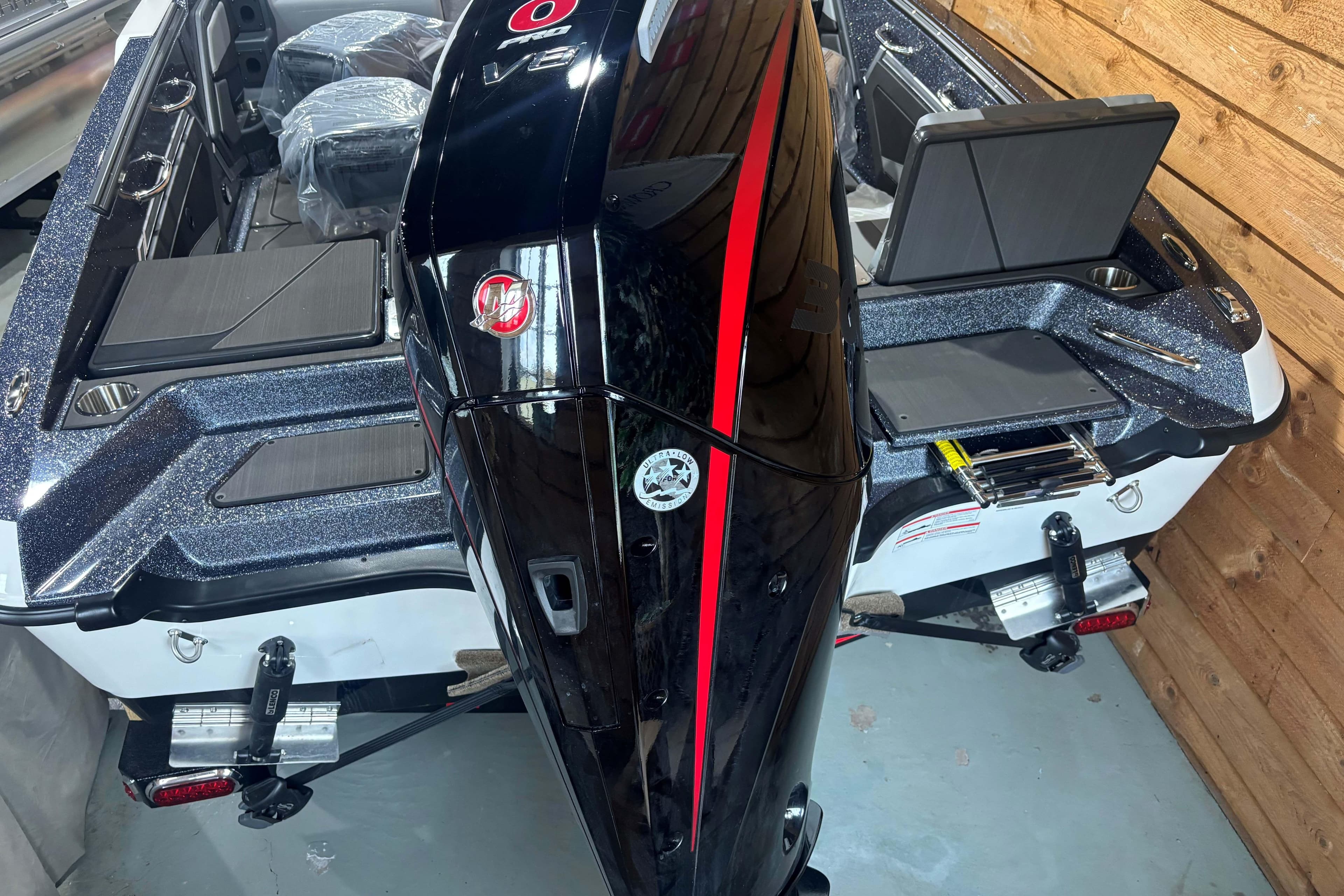 2026 Lund 202 Pro-V GL boat with powerful outboard motor in a showroom.