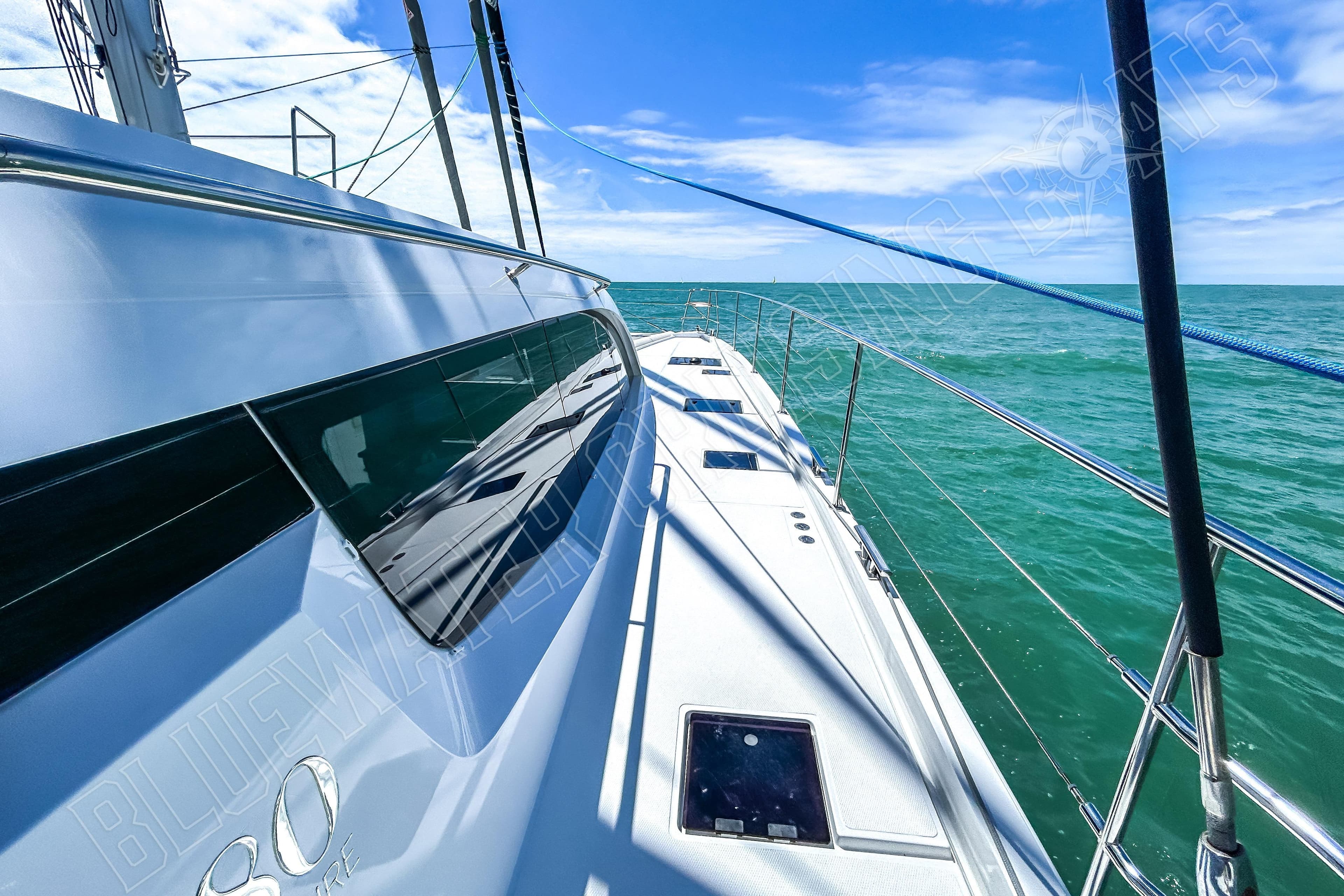 Sleek Privilege 580 yacht sailing on turquoise sea under clear blue sky, 2025 model.