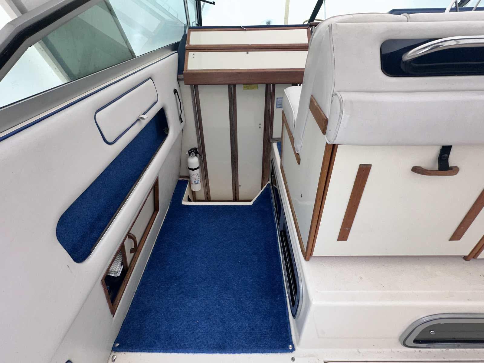 Interior of 1987 Sea Ray 270 Sundancer boat with blue carpet and white seating.